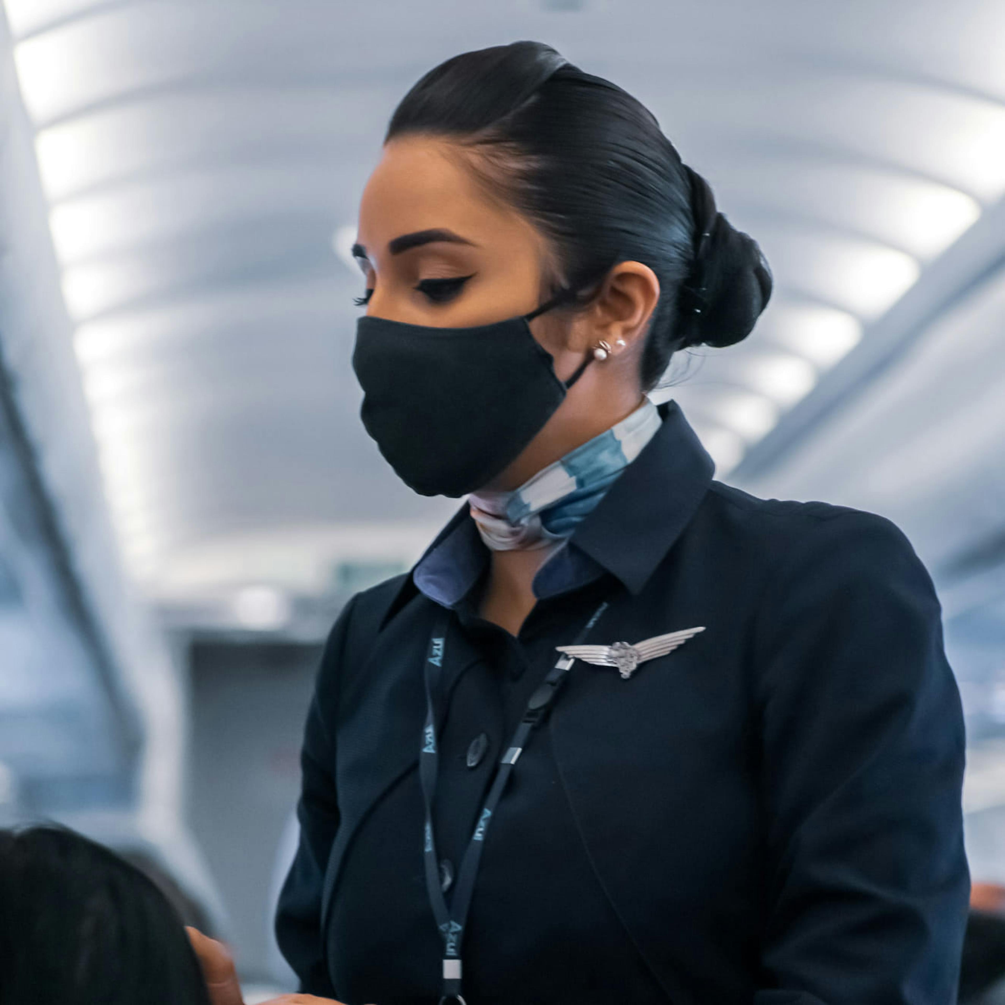 A flight attendant gently reminding a passenger to wear a face mask on the plane during the pandemic.