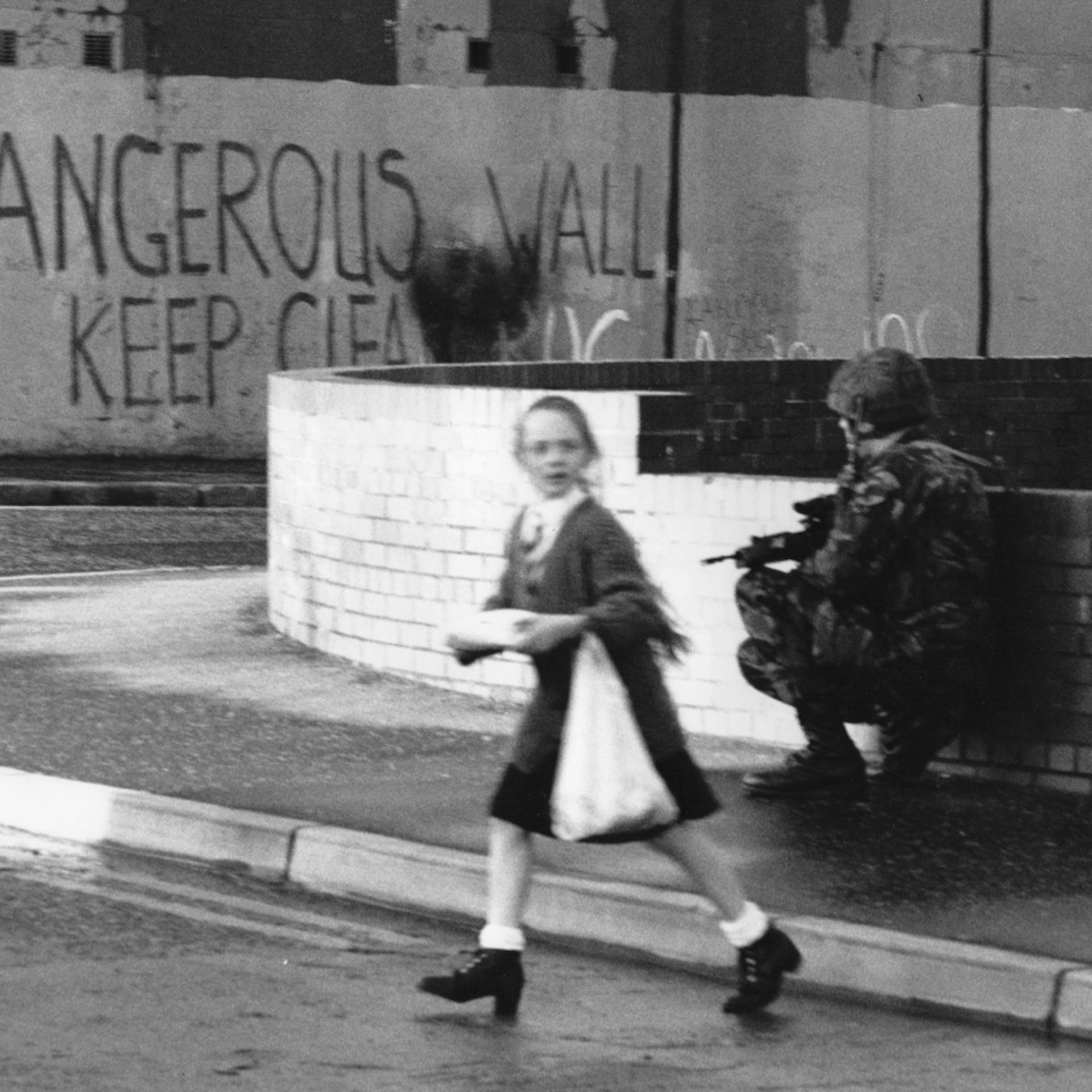 A young Irish girl crosses the street in 20th-century Belfast, Ireland amidst IRA conflicts.