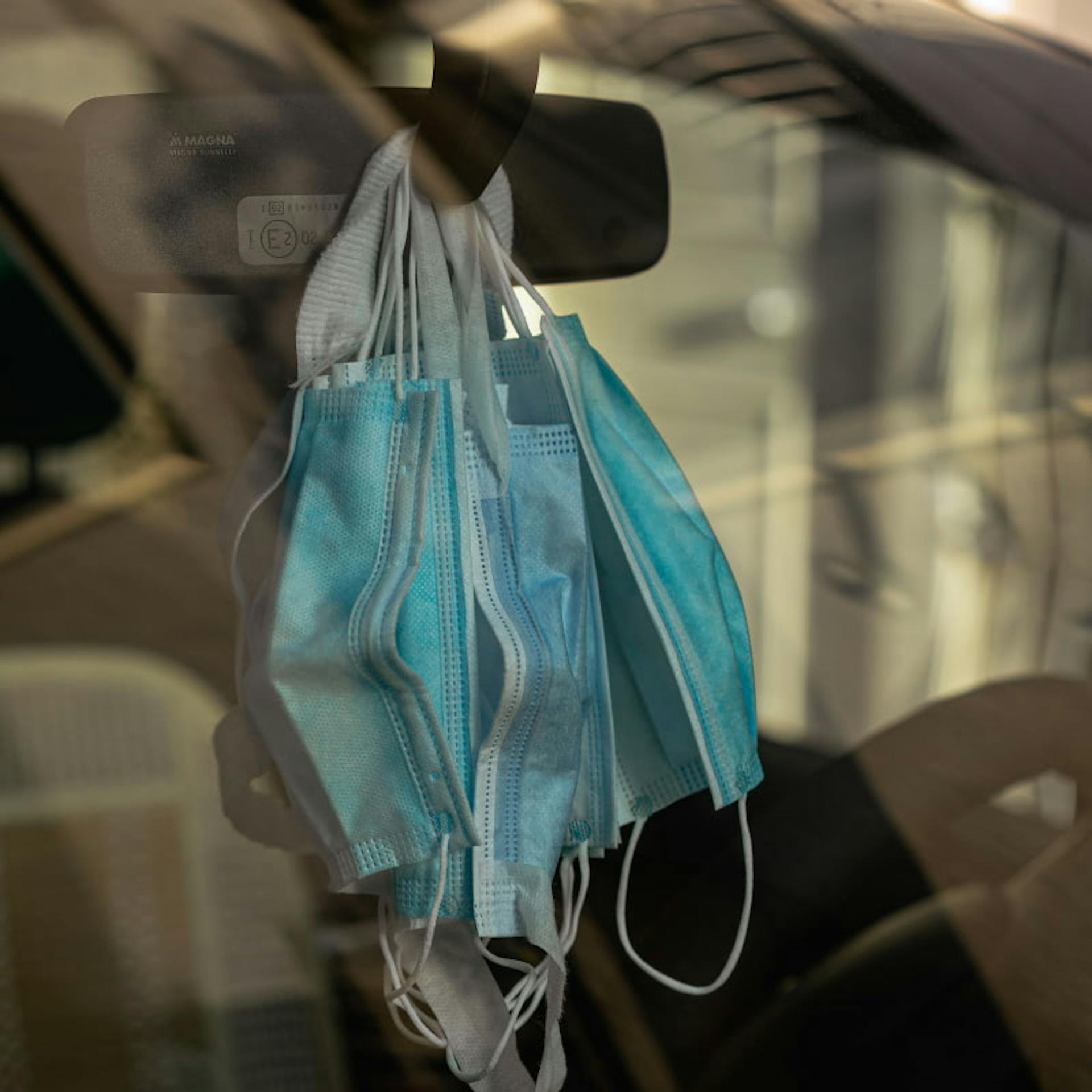 A person keeps a cache of face masks on their rearview window to remind them to put one on whenever they get out of their car.