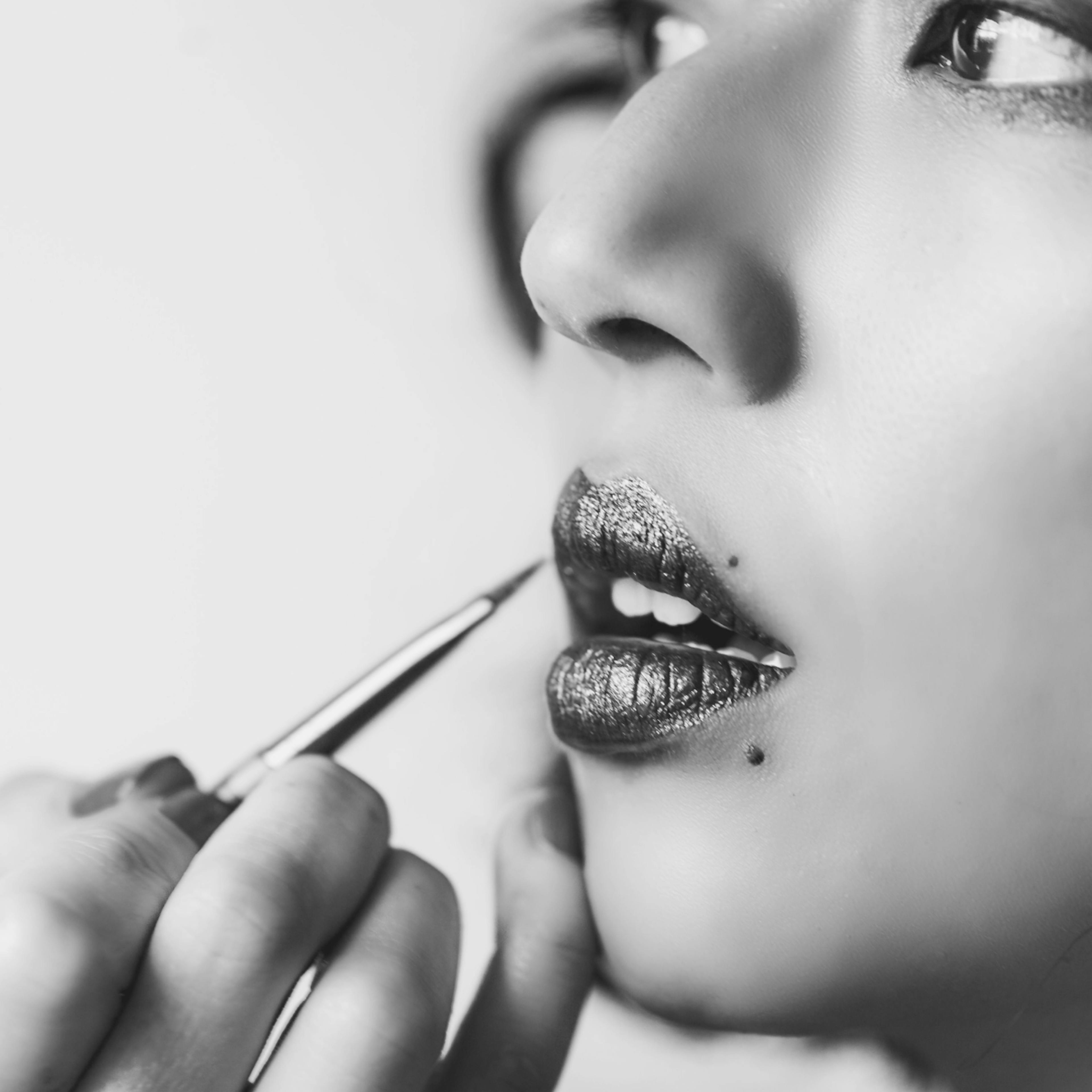 A woman applies makeup to create a mask for herself in society.