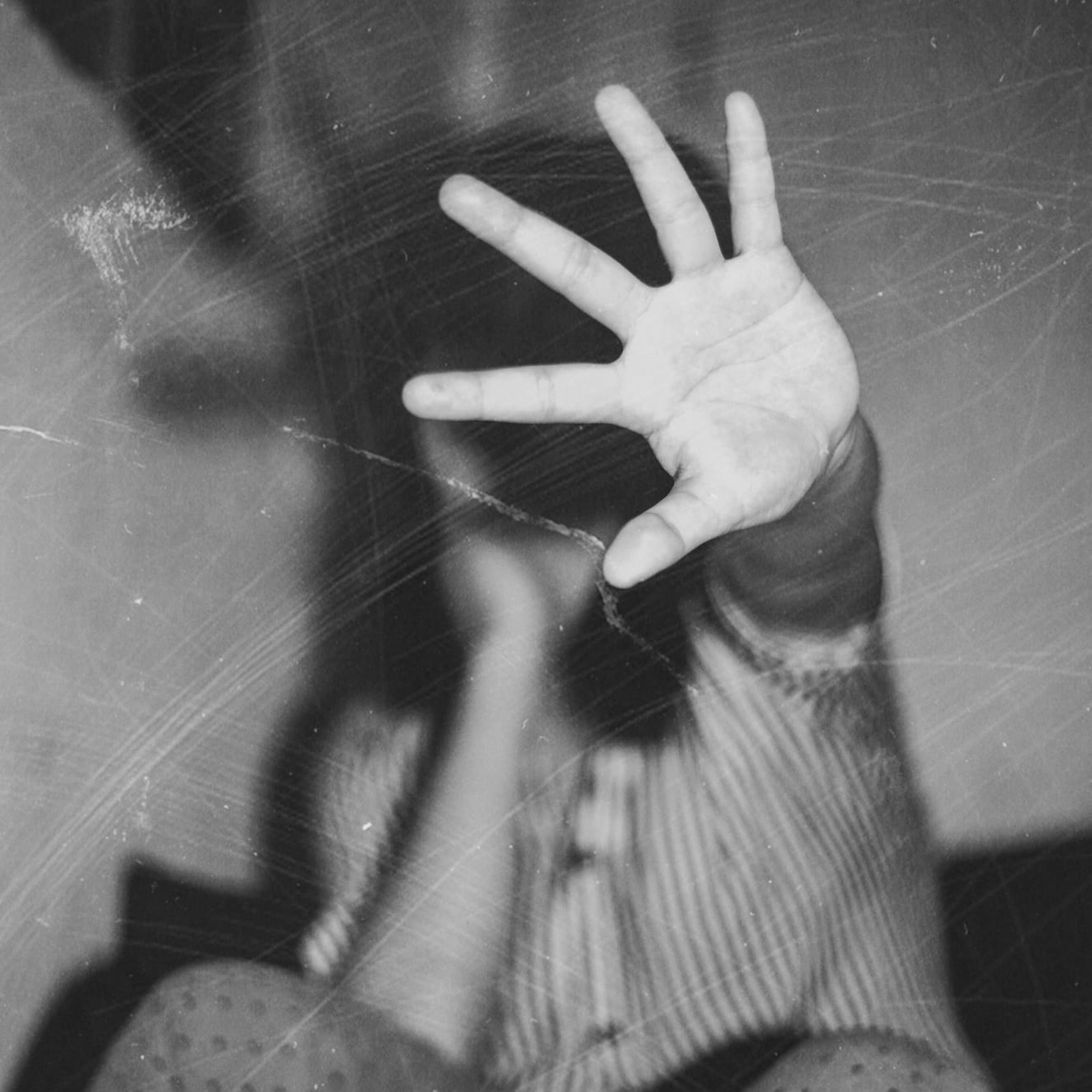 An old, scratched photo of a family member holding a hand up to stop the photographer from capturing their image.