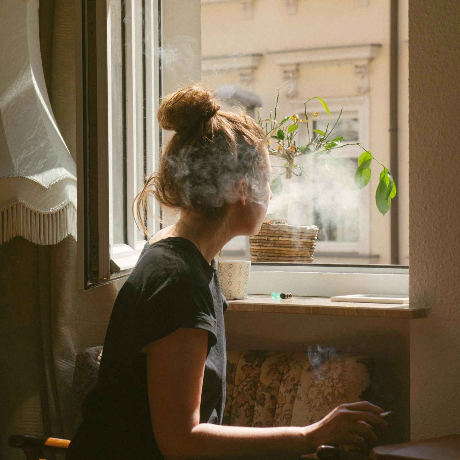 Girl blowing smoke out of the window