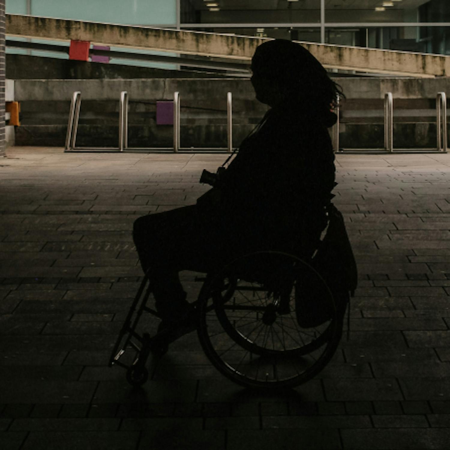 Silhouette of woman in wheelchair outside.