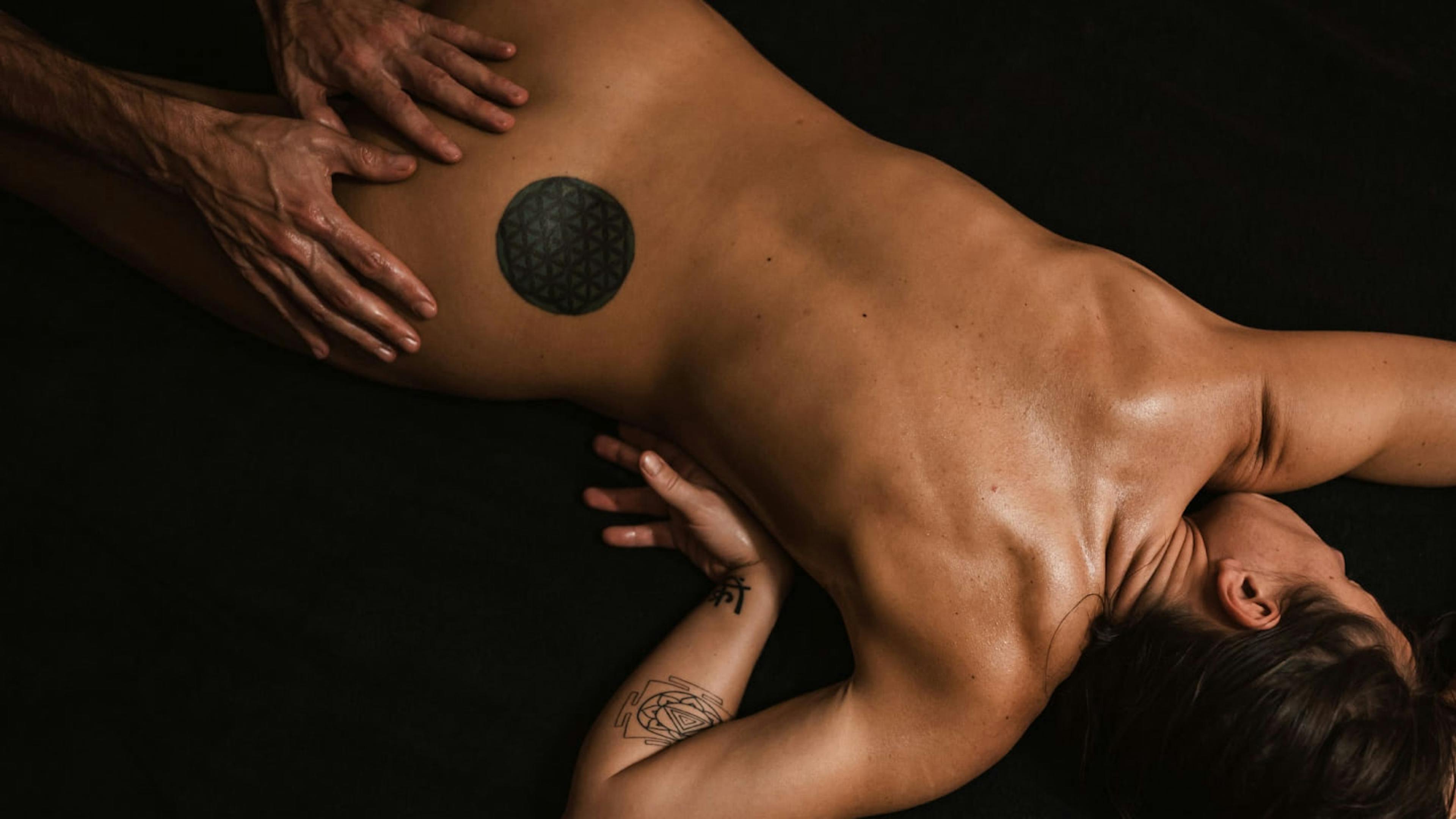 A man performs tantric massage on a female partner.