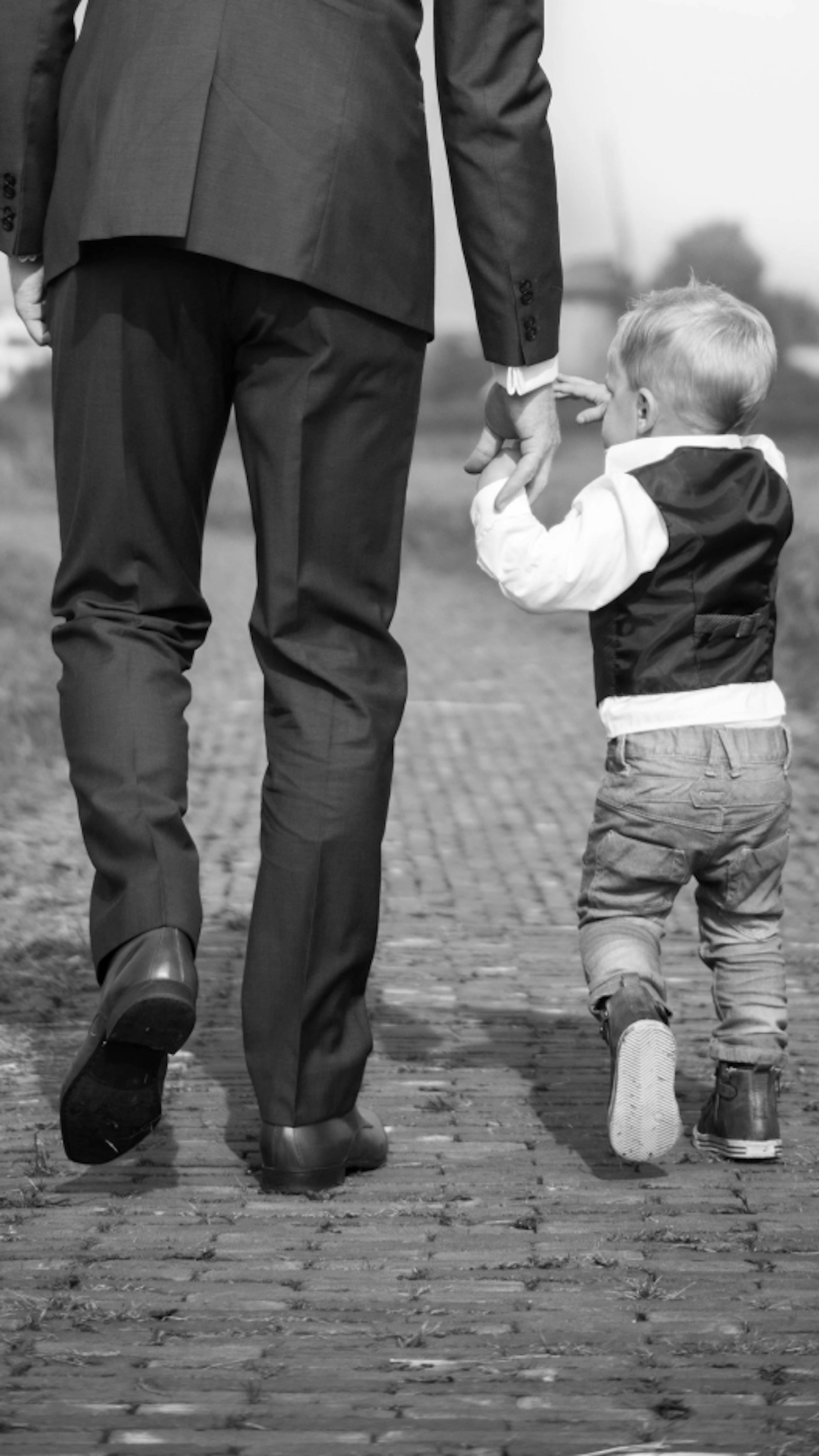 A man and child walking, holding hands.