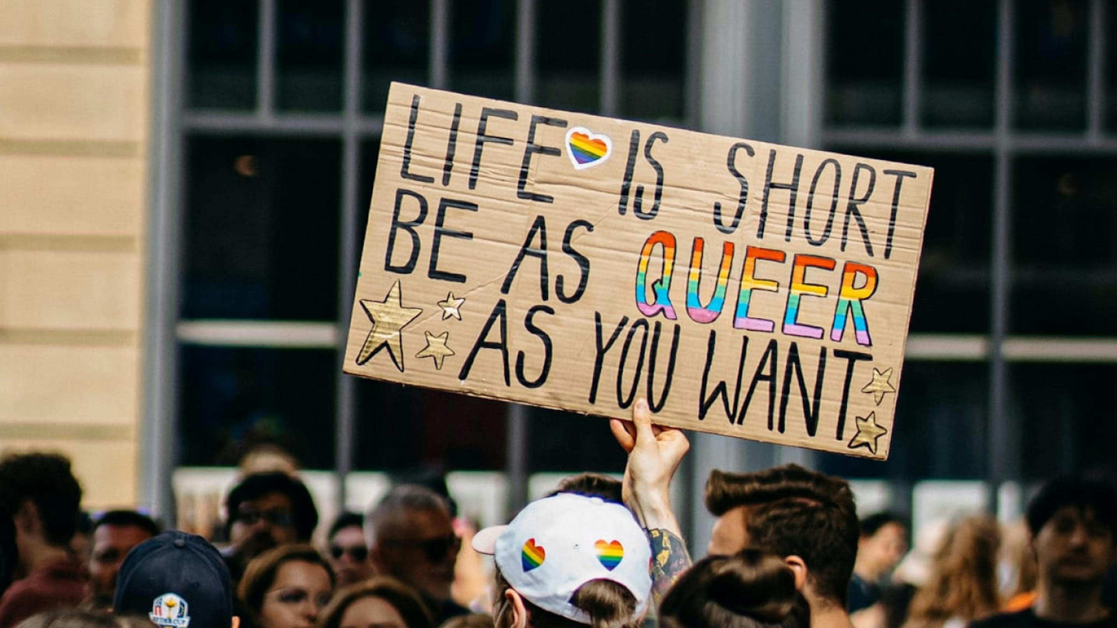 A sign at a LGBTQ+ Pride parade that reads "Life is short, be as queer as you want."