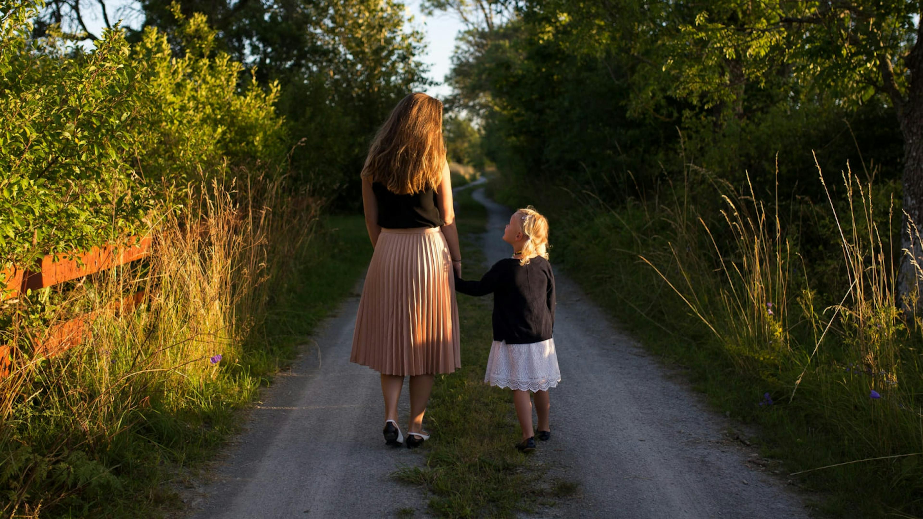 A mother walks her child down a road.