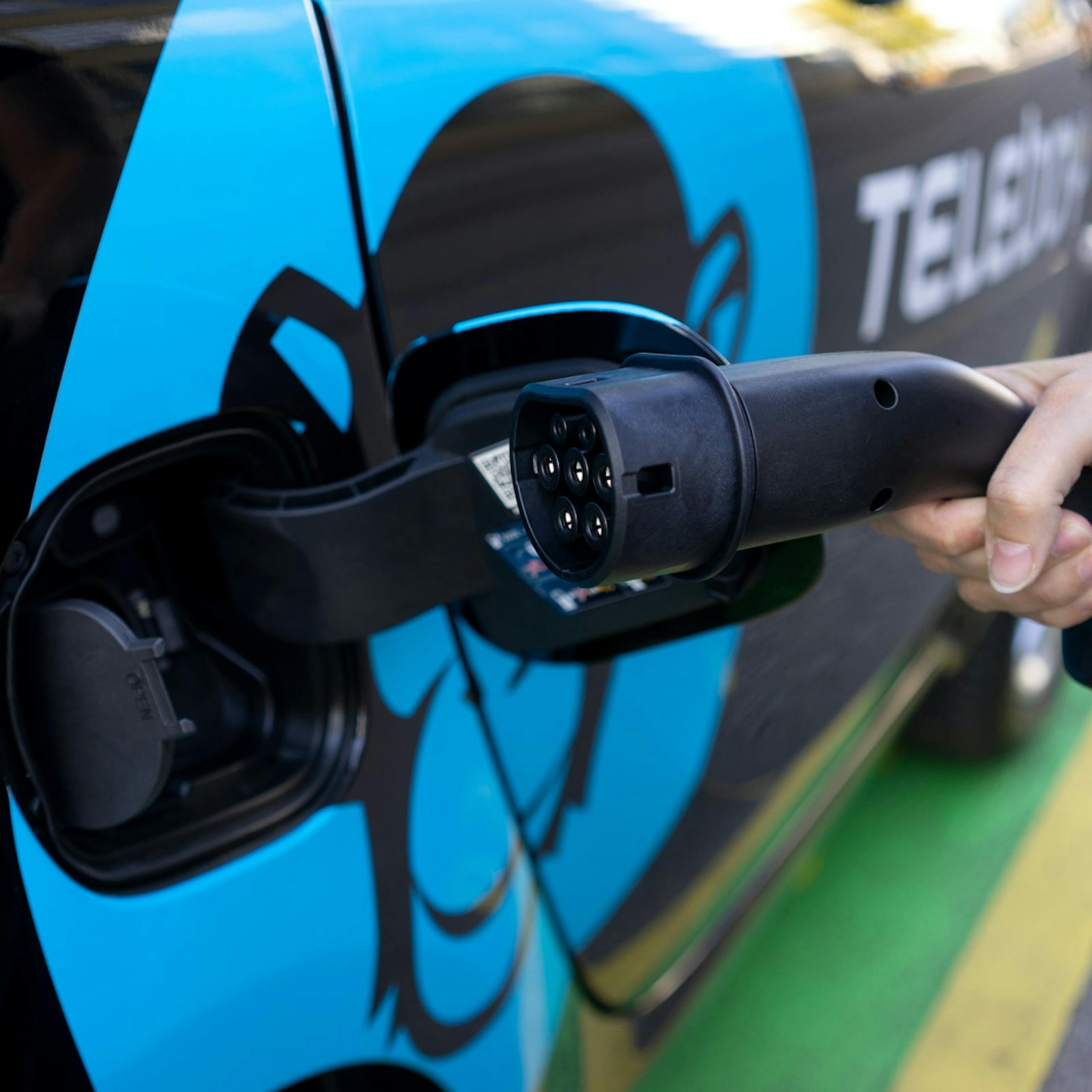An electric car being charged shows a small part of combating climate change challenges