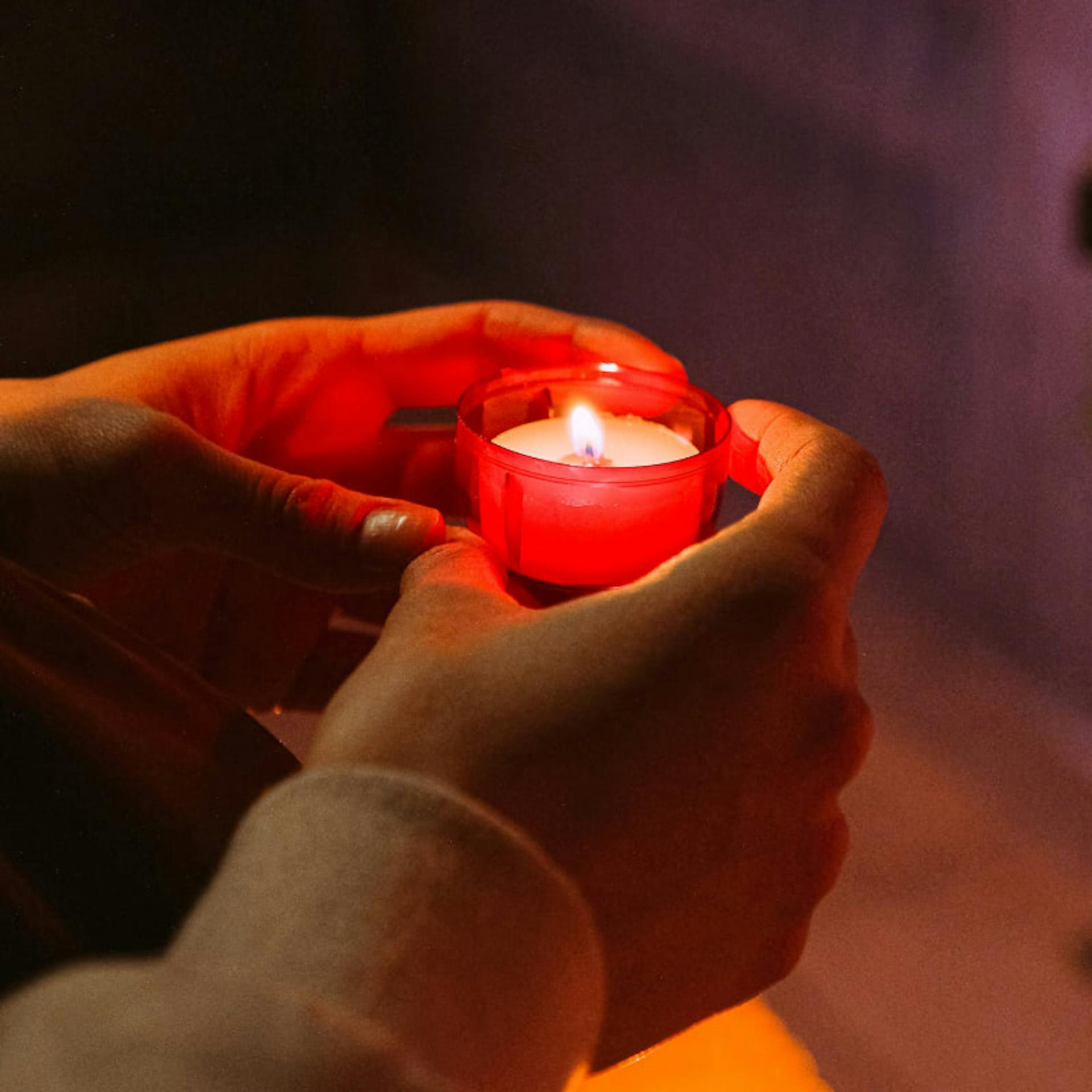 A woman lights a candle in prayer after being impregnated through rape.