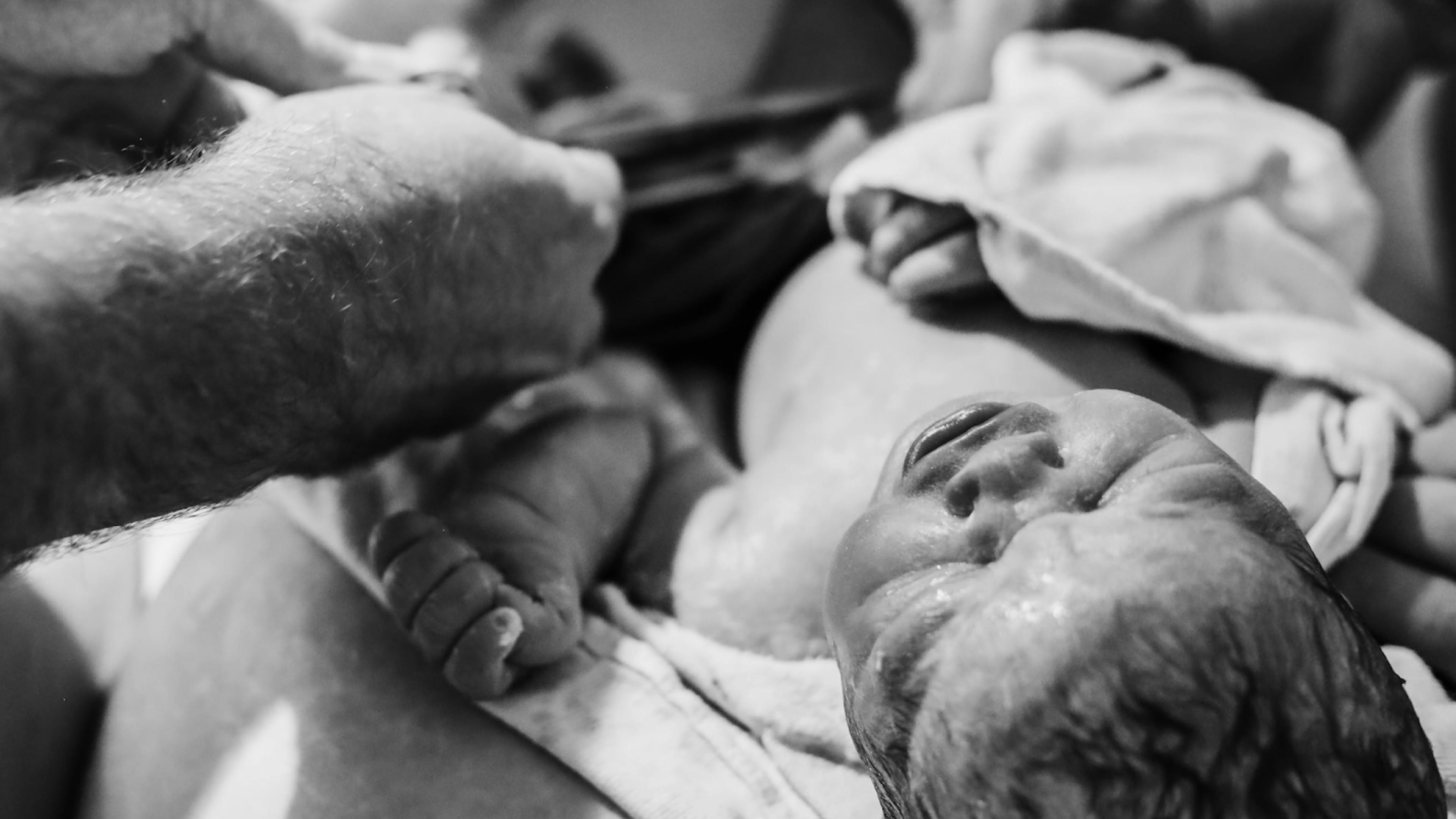 A baby is cleaned and the umbilical cord is cut during a home birth.