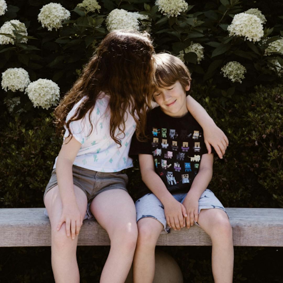 Young brother and sister are affectionate on a bench.