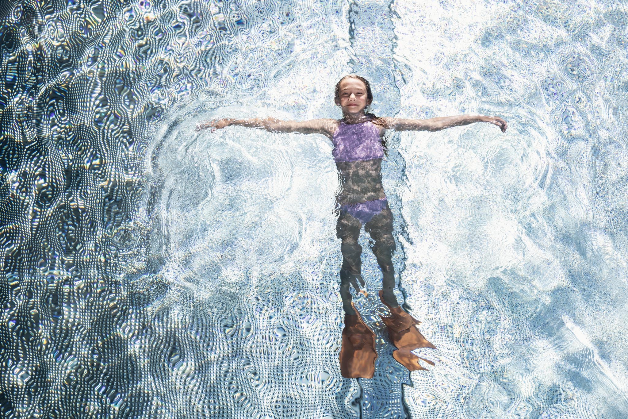 Kind liegt mit Schwimmflossen im Pool eines Familux Resorts