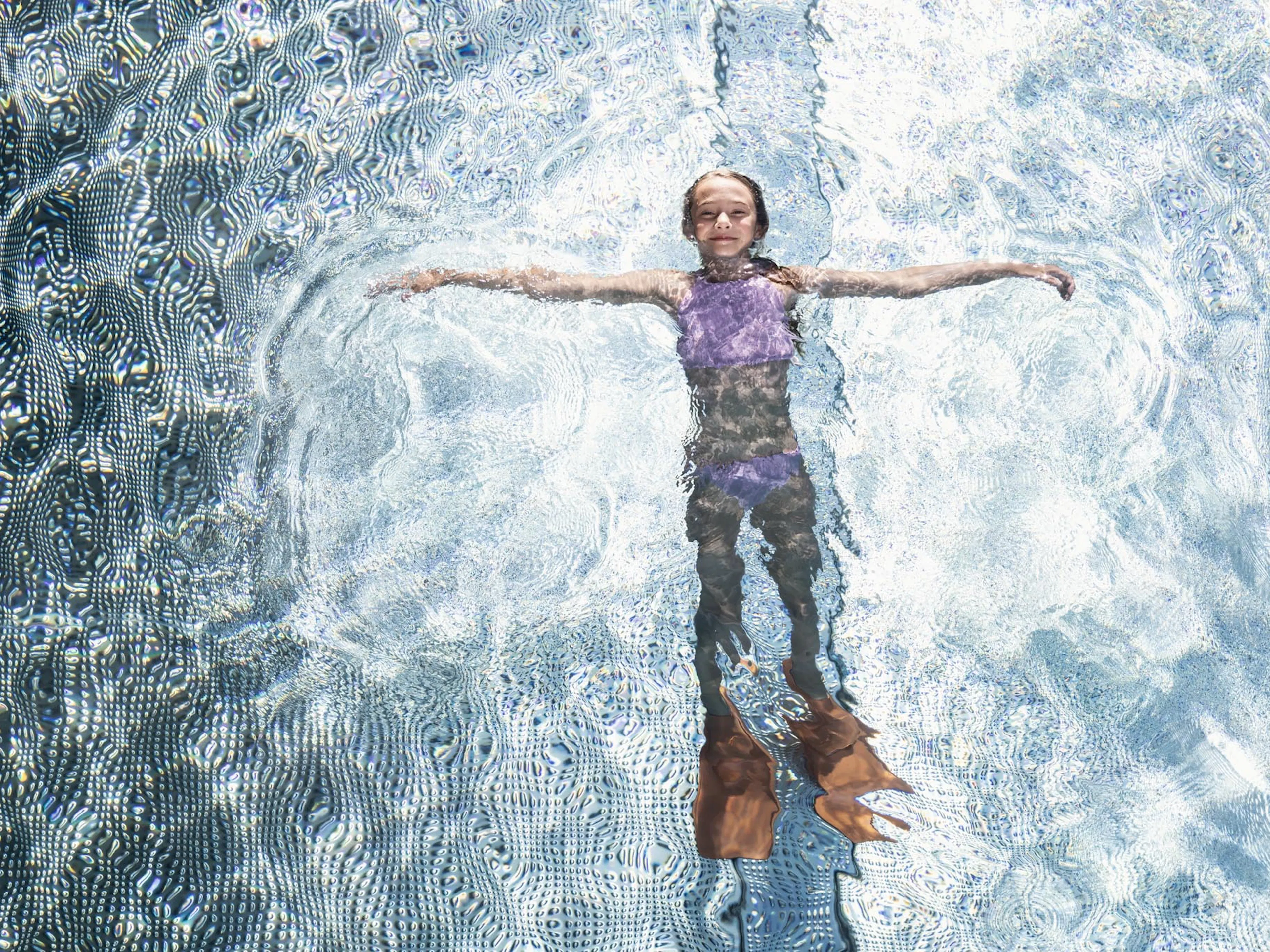 Kind liegt mit Schwimmflossen im Pool eines Familux Resorts