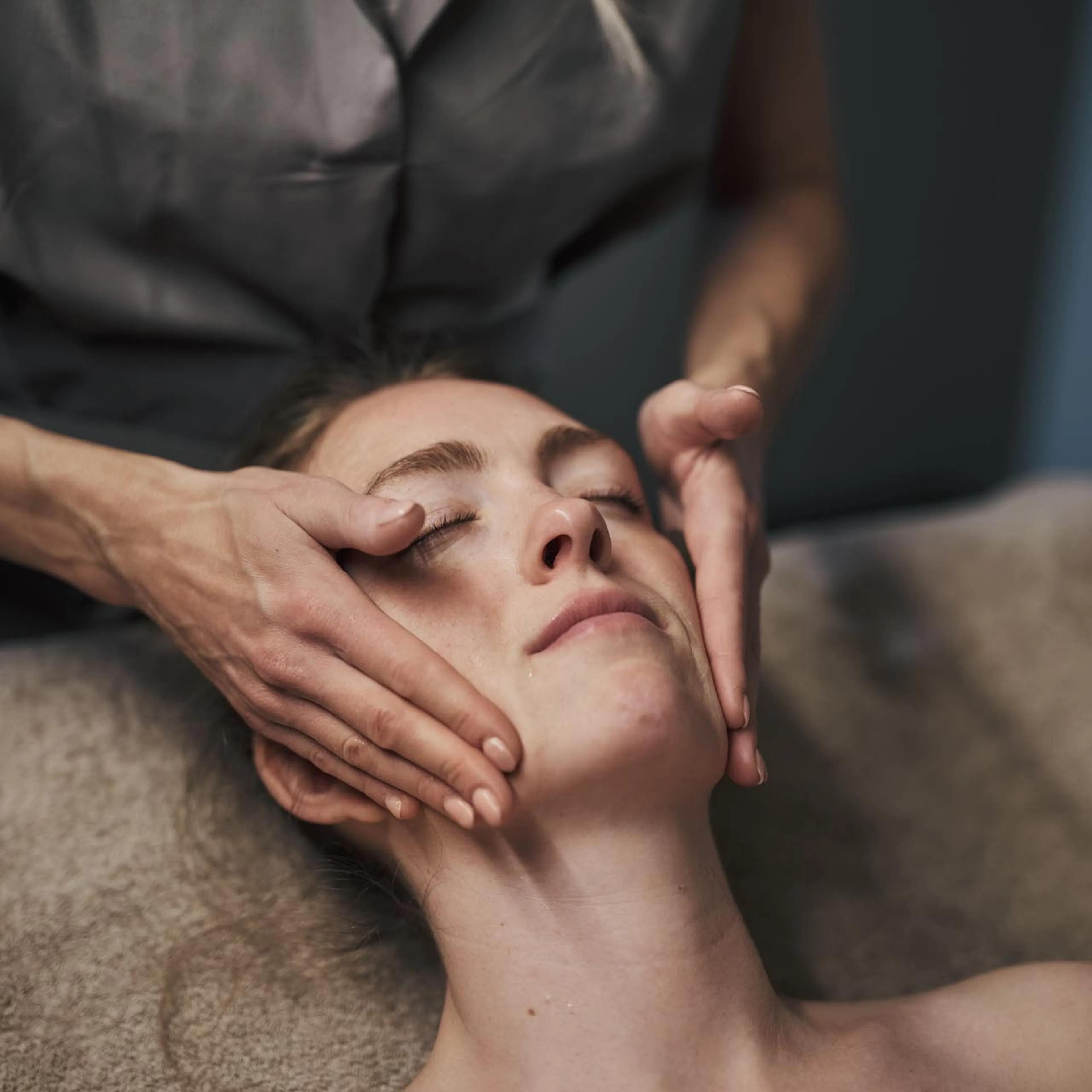Woman receiving a facial treatment in a treatment room at the Alpenrose – Familux Resort.