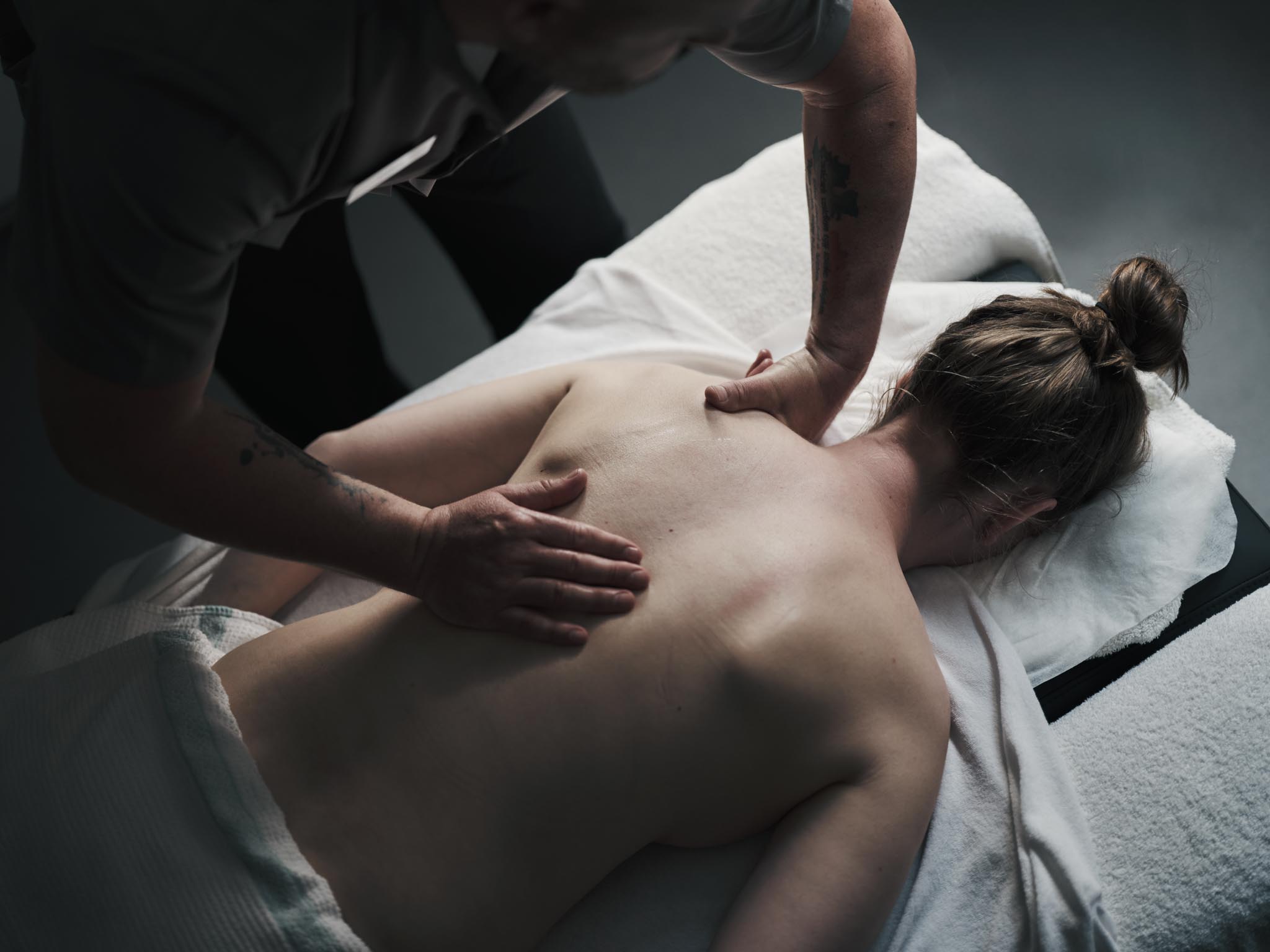 Frau bekommt Rückenmassage in einem Behandlungsraum des Alpenrose Familux Resorts.