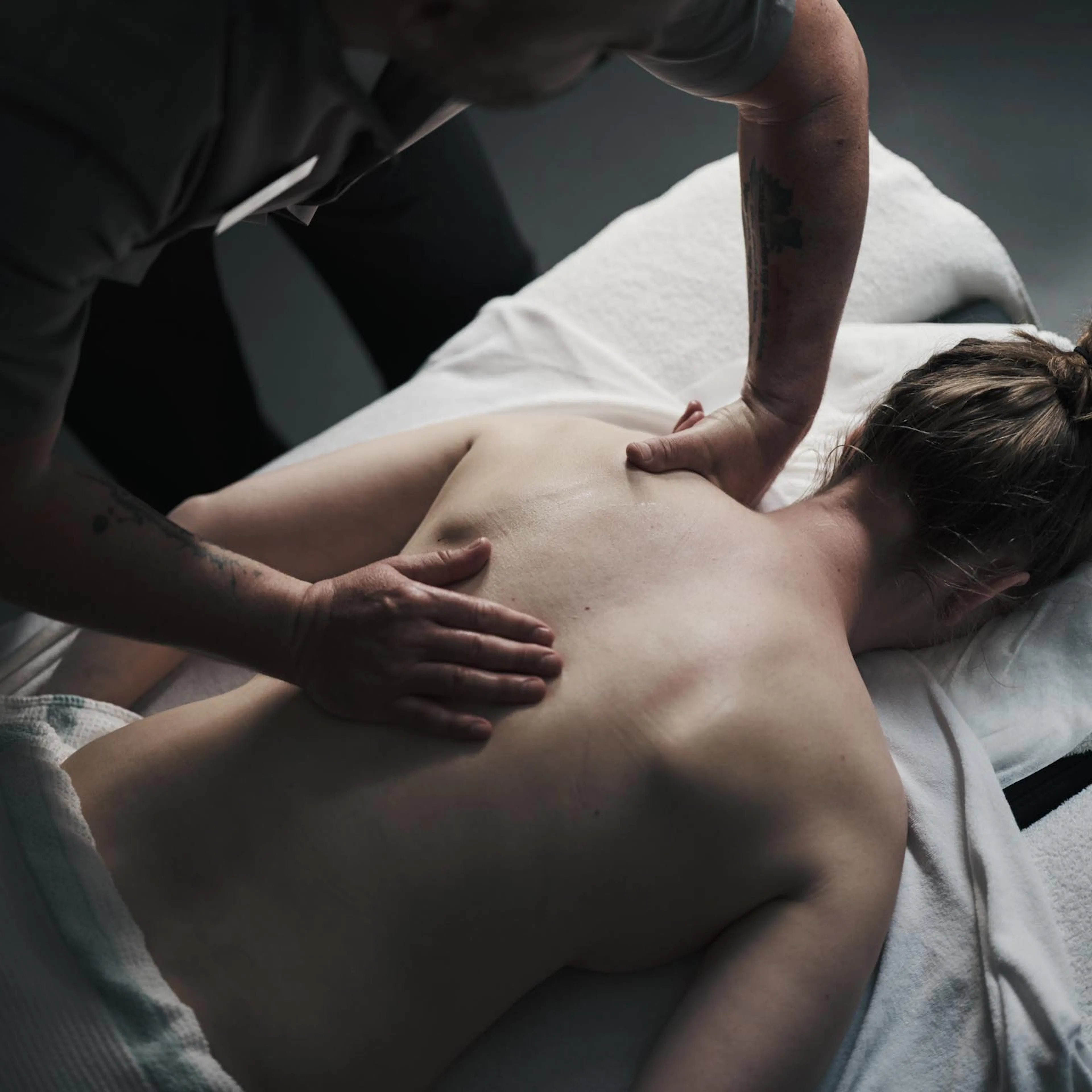 Frau bekommt Rückenmassage in einem Behandlungsraum des Alpenrose Familux Resorts.