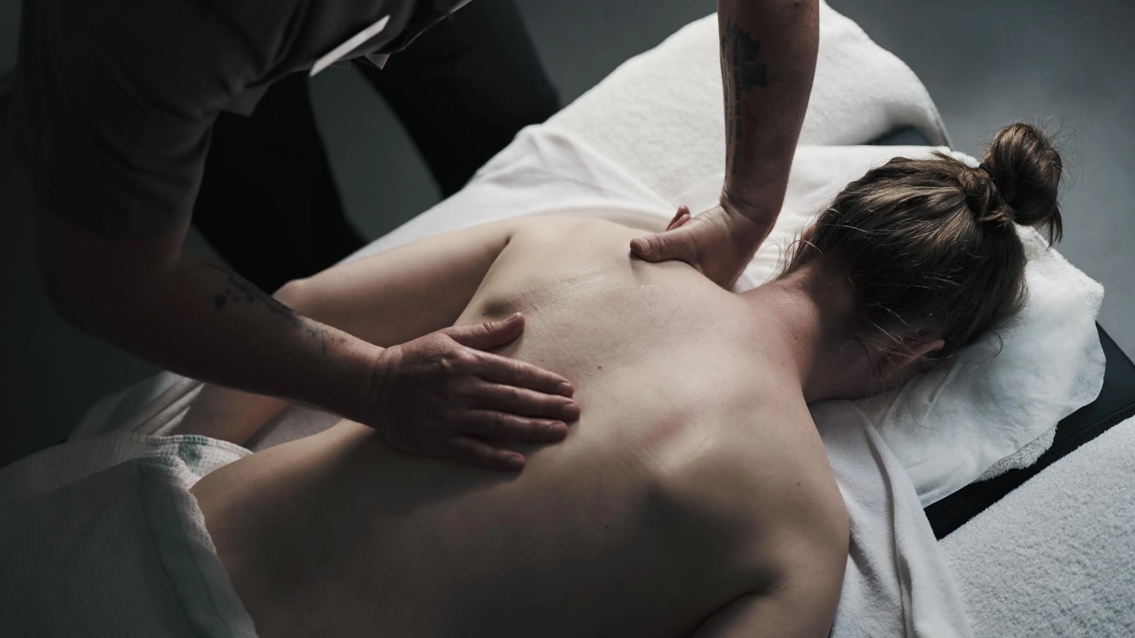 Frau bekommt Rückenmassage in einem Behandlungsraum des Alpenrose Familux Resorts.