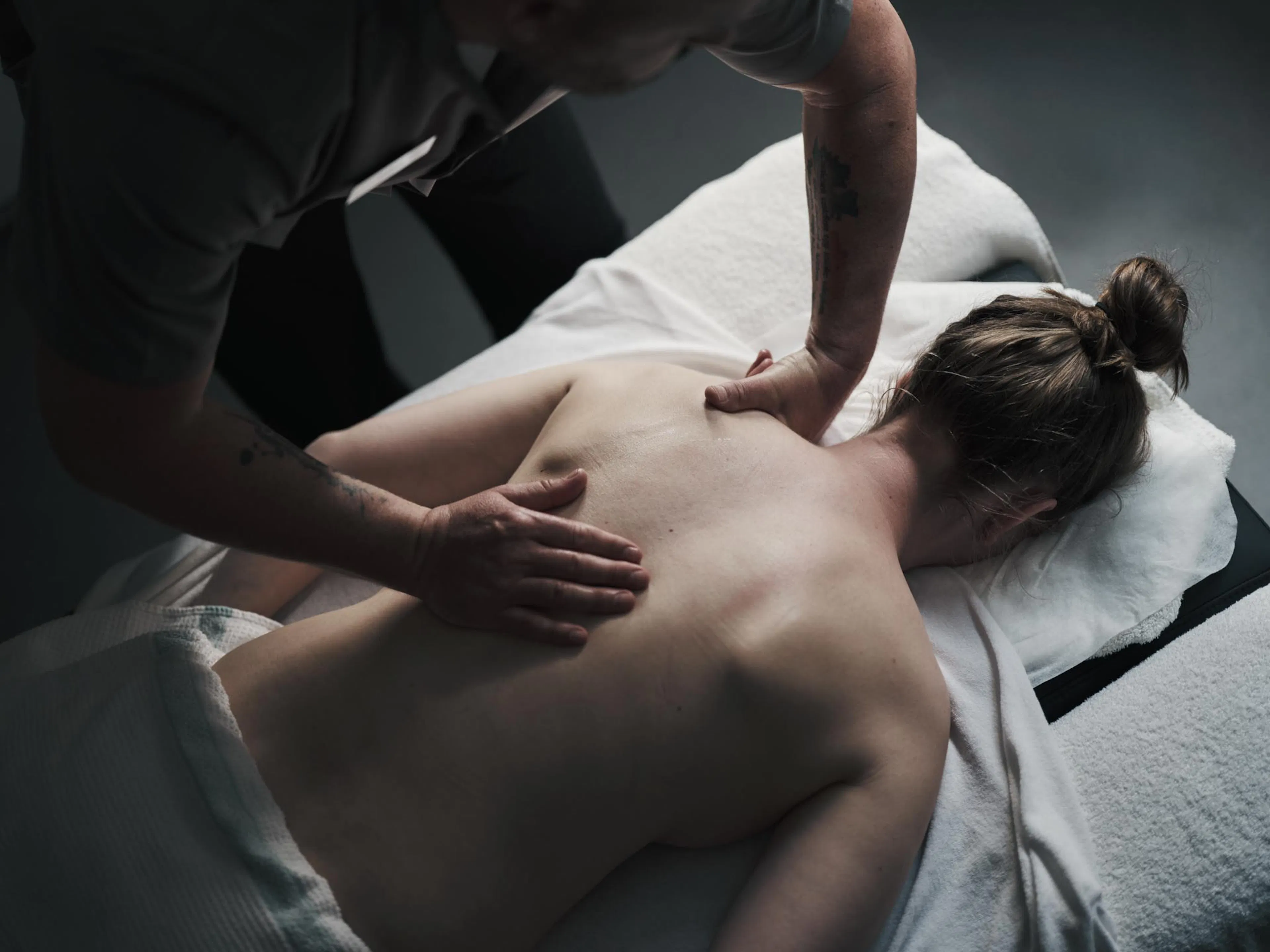 Frau bekommt Rückenmassage in einem Behandlungsraum des Alpenrose Familux Resorts.