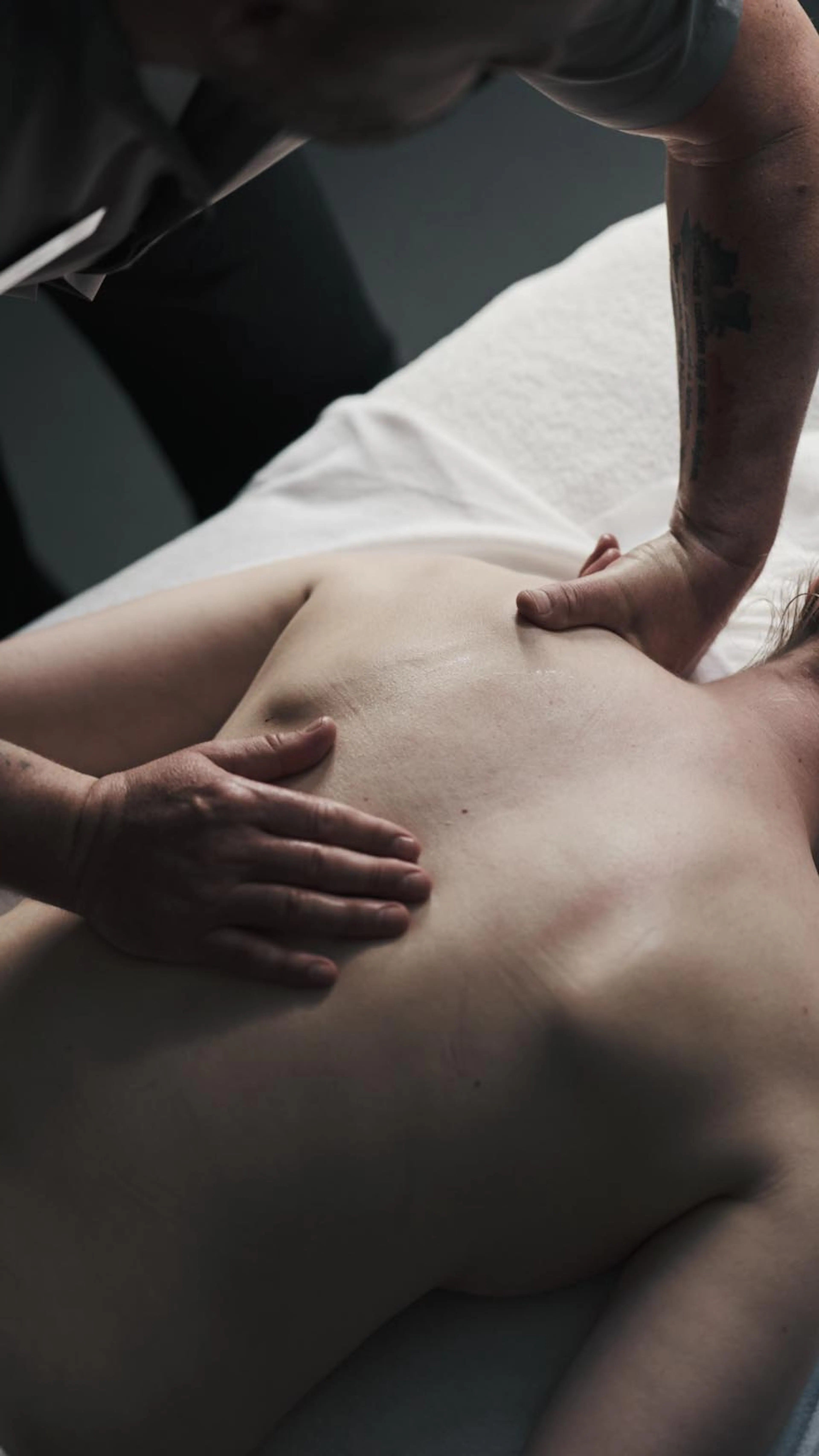 Frau bekommt Rückenmassage in einem Behandlungsraum des Alpenrose Familux Resorts.