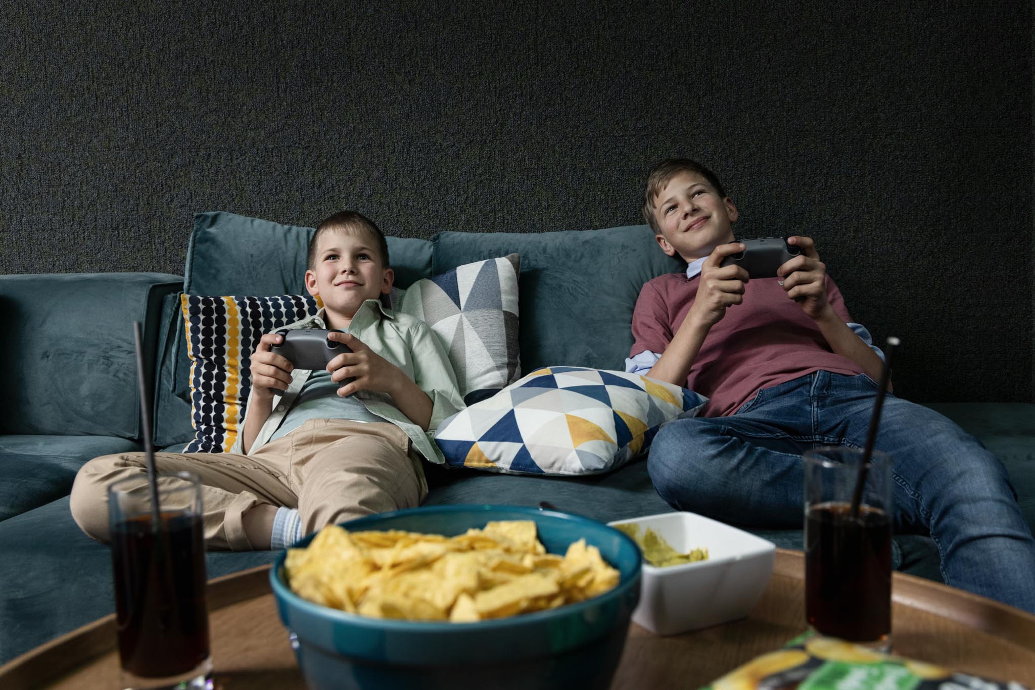 Two boys playing on the PlayStation in the teen club at the Dachsteinkönig – Familux Resort.