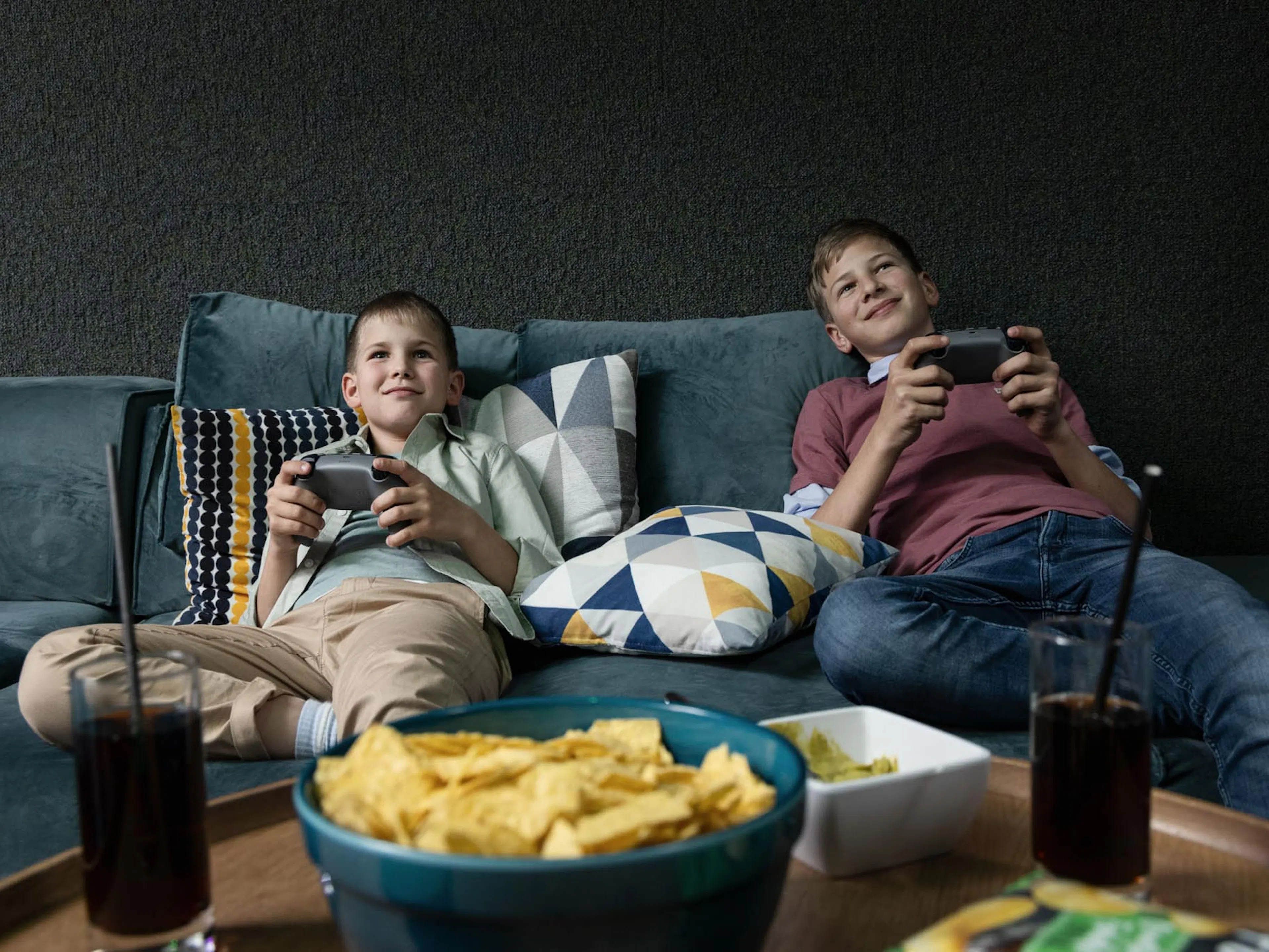Two boys playing on the PlayStation in the teen club at the Dachsteinkönig – Familux Resort.