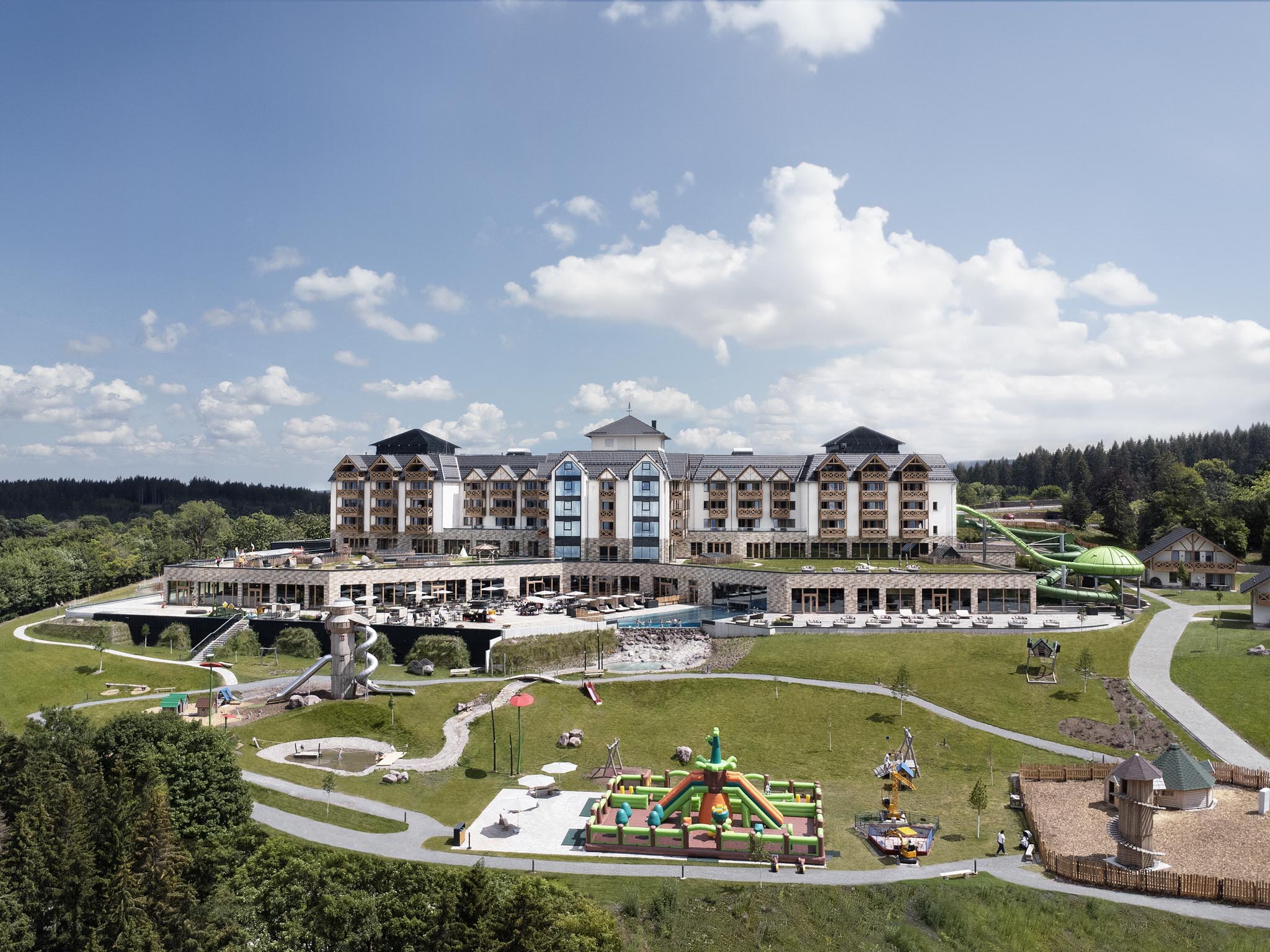 Summer exterior view of The Grand Green – Familux Resort with playground.