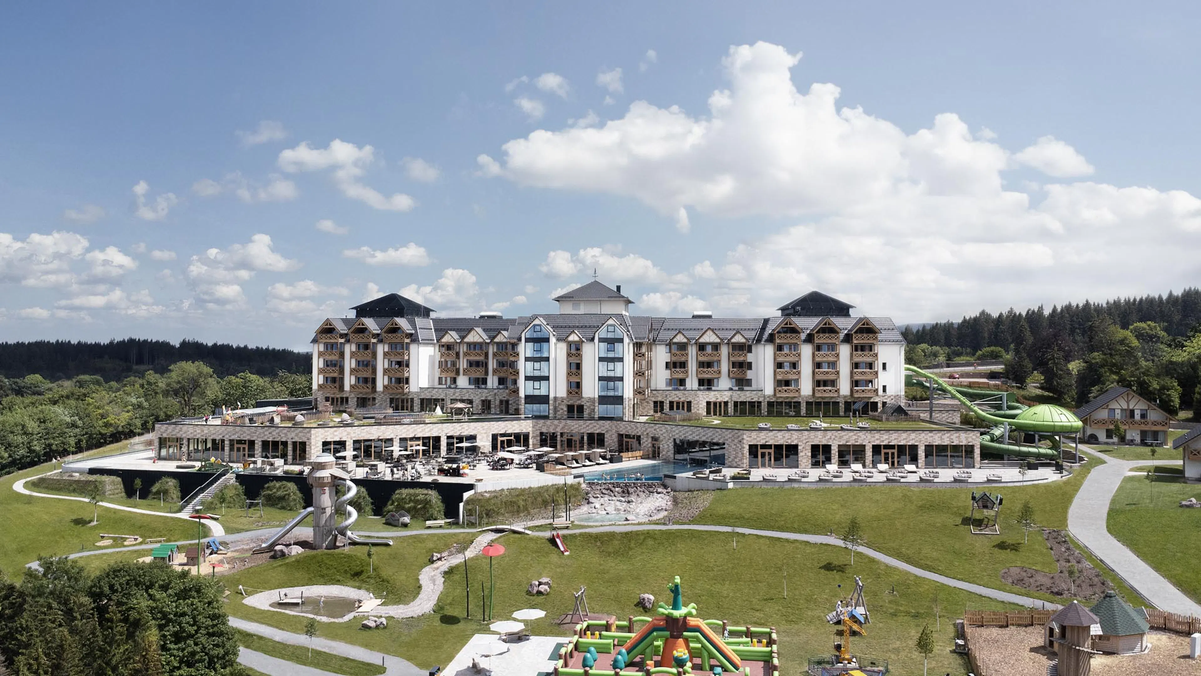 Summer exterior view of The Grand Green – Familux Resort with playground.