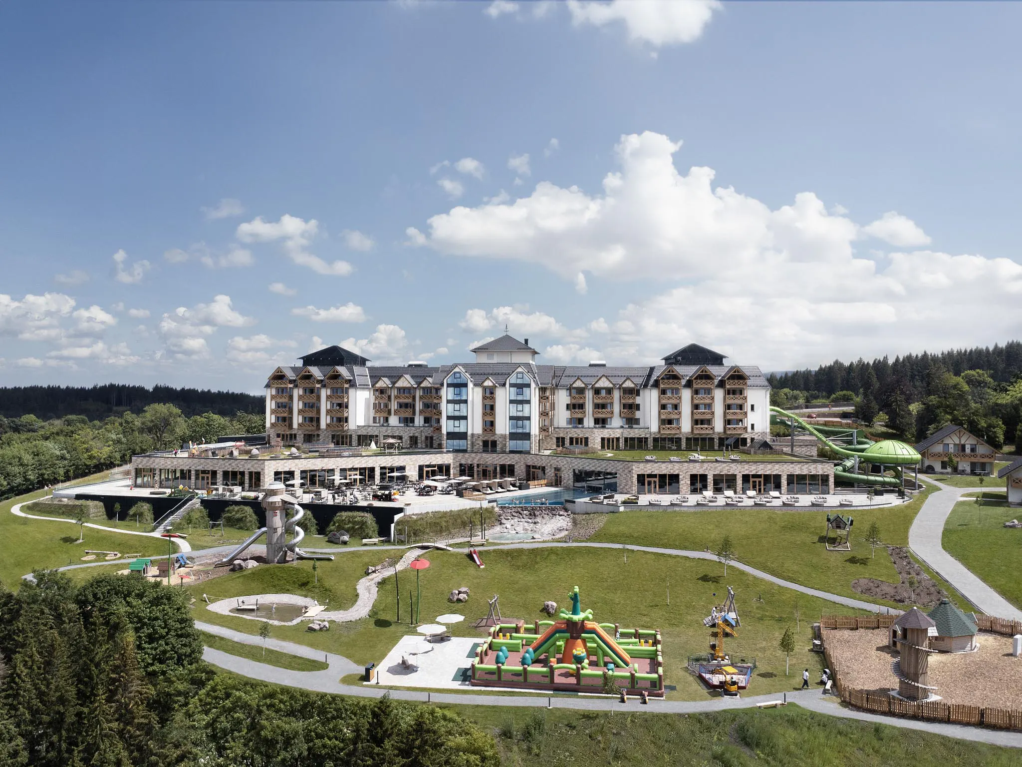 Sommerliche Hotelansicht des The Grand Green - Familux Resorts mit Spielplatz.