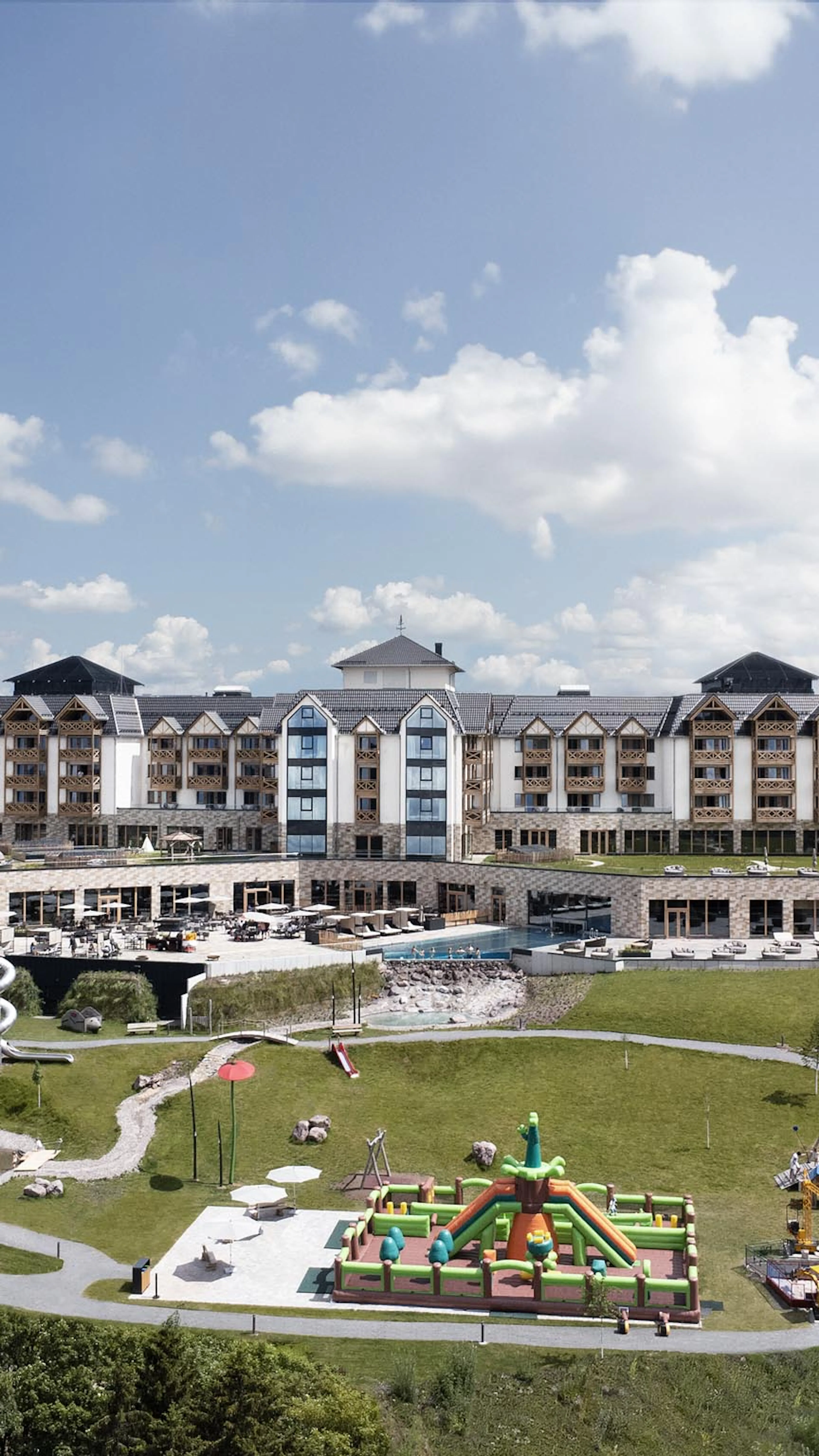 Sommerliche Hotelansicht des The Grand Green - Familux Resorts mit Spielplatz.