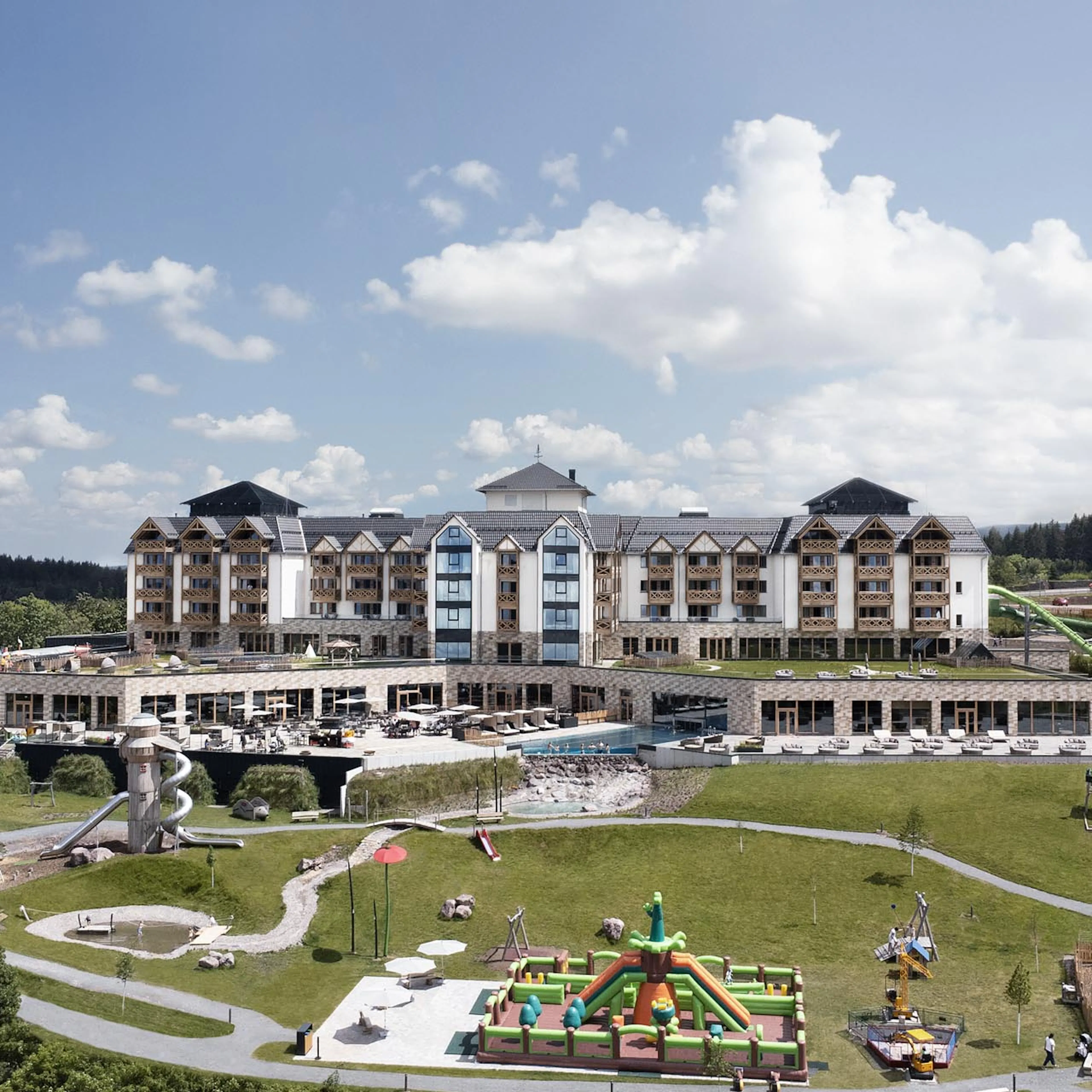Sommerliche Hotelansicht des The Grand Green - Familux Resorts mit Spielplatz.