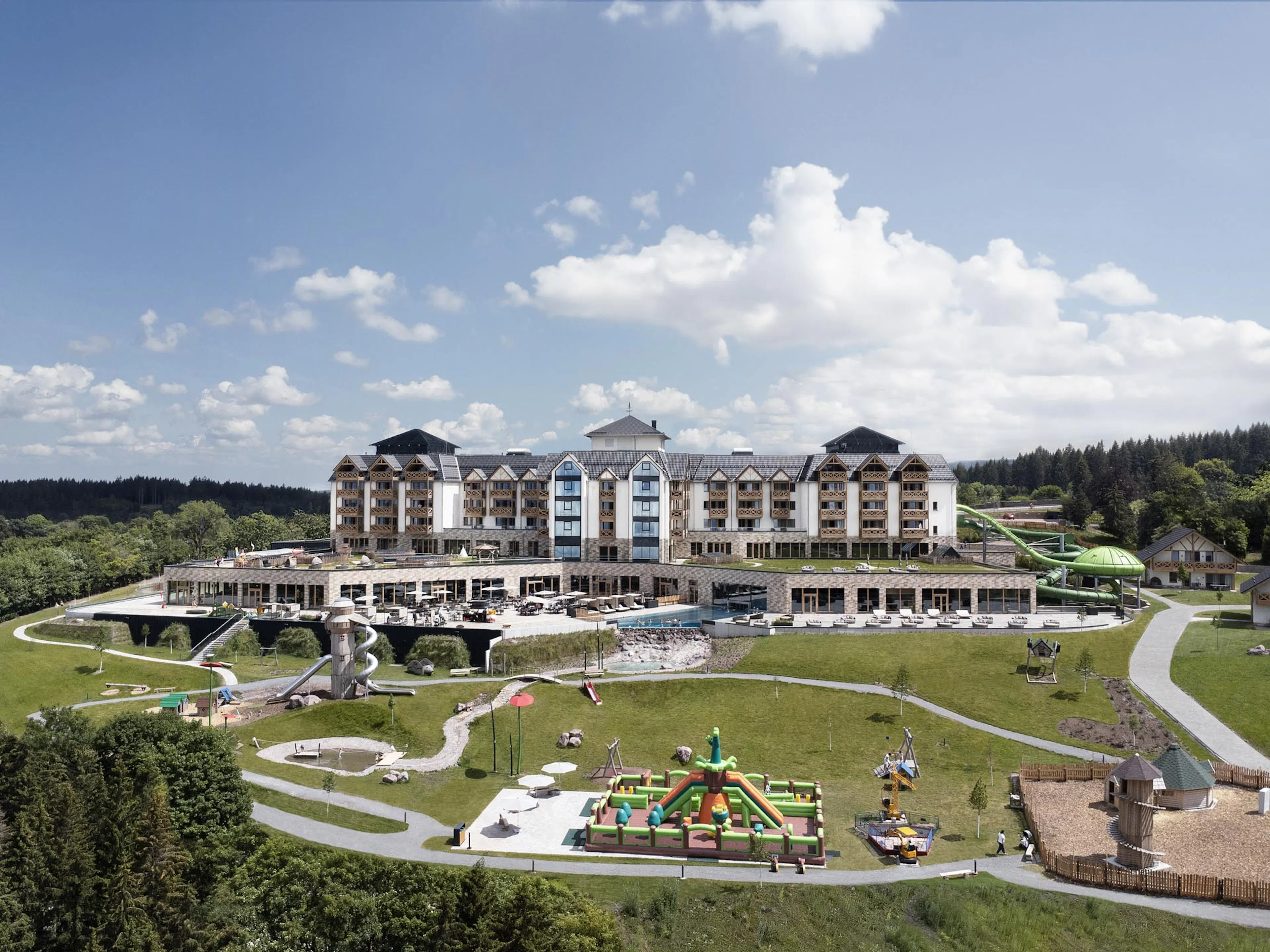 Sommerliche Hotelansicht des The Grand Green - Familux Resorts mit Spielplatz.