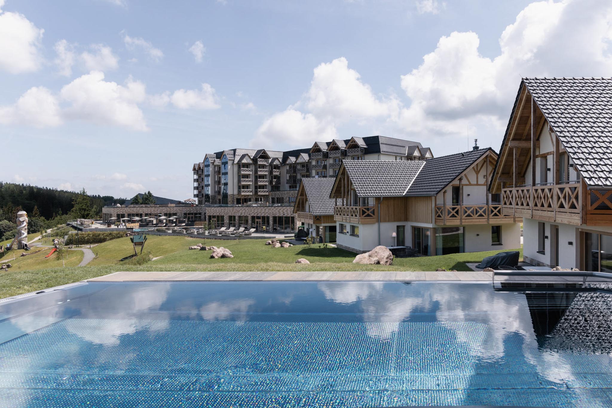 Hotel exterior with chalet and pool at The Grand Green – Familux Resort.