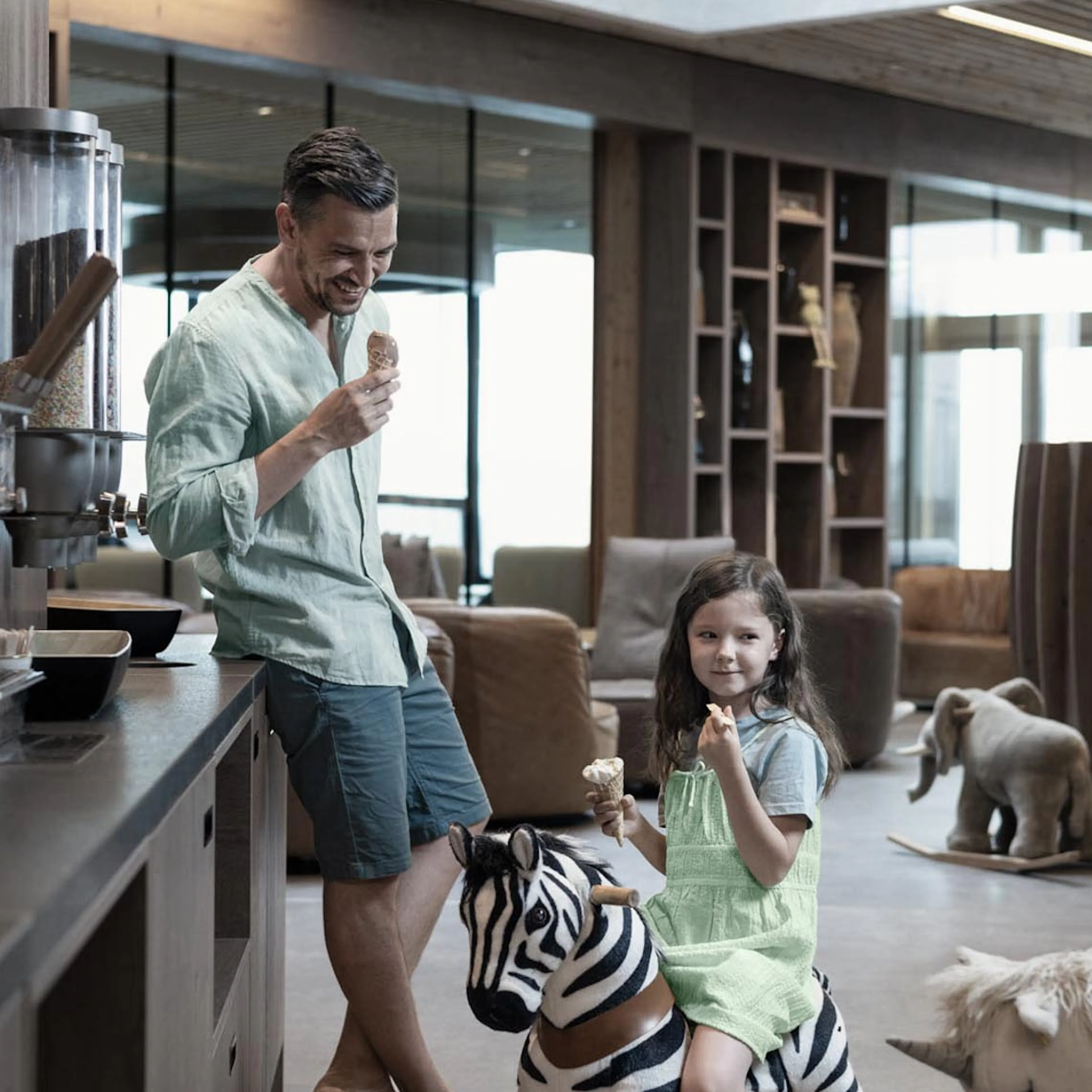 Papa und Kind essen ein Softeis im Restaurant des The Grand Green - Familux Resorts.