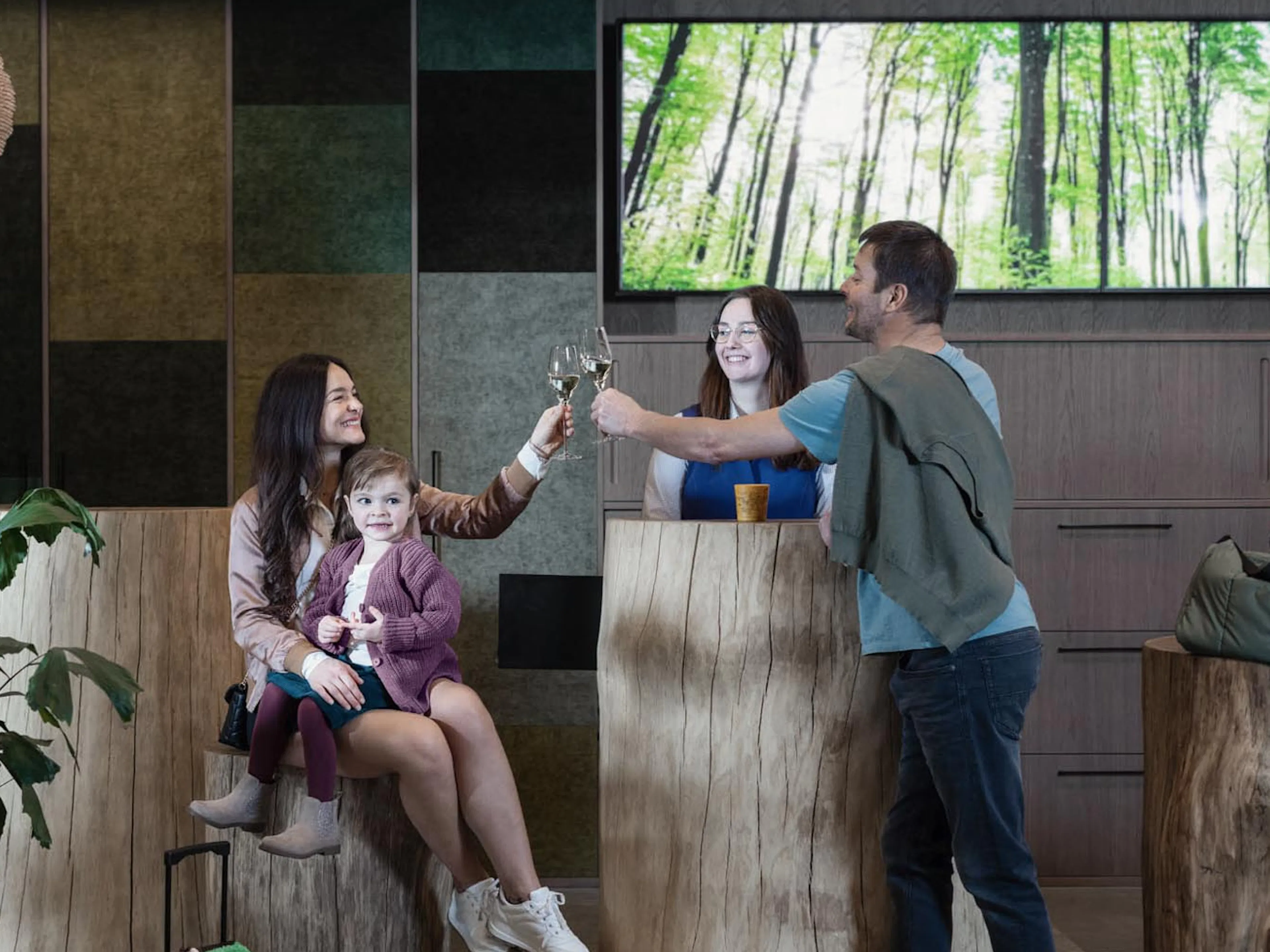 Family checking in with a member of staff at The Grand Green – Familux Resort whilst enjoying a glass of sparkling wine.