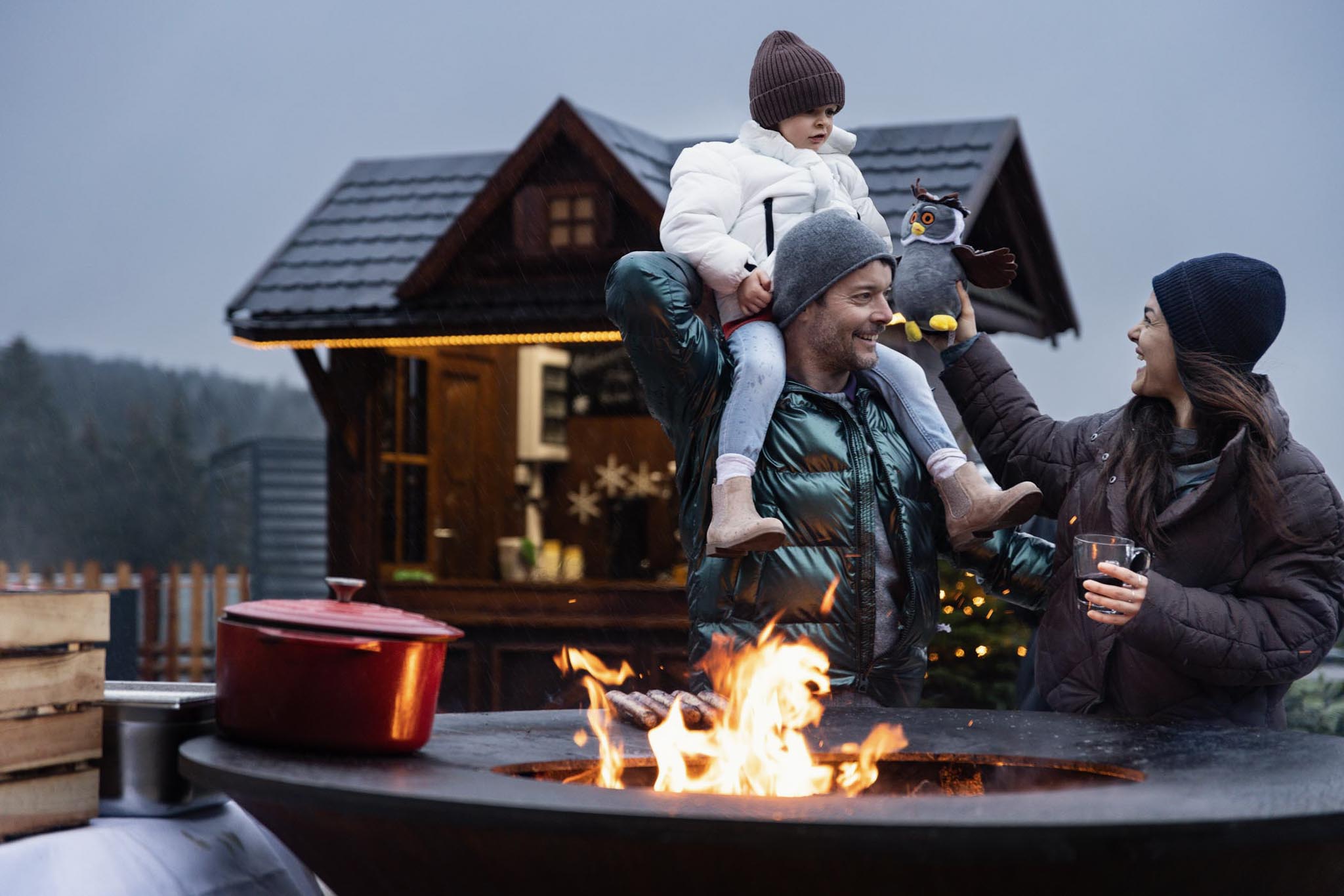 Family standing at the Ofyr grill in winter on the terrace of The Grand Green – Familux Resort.