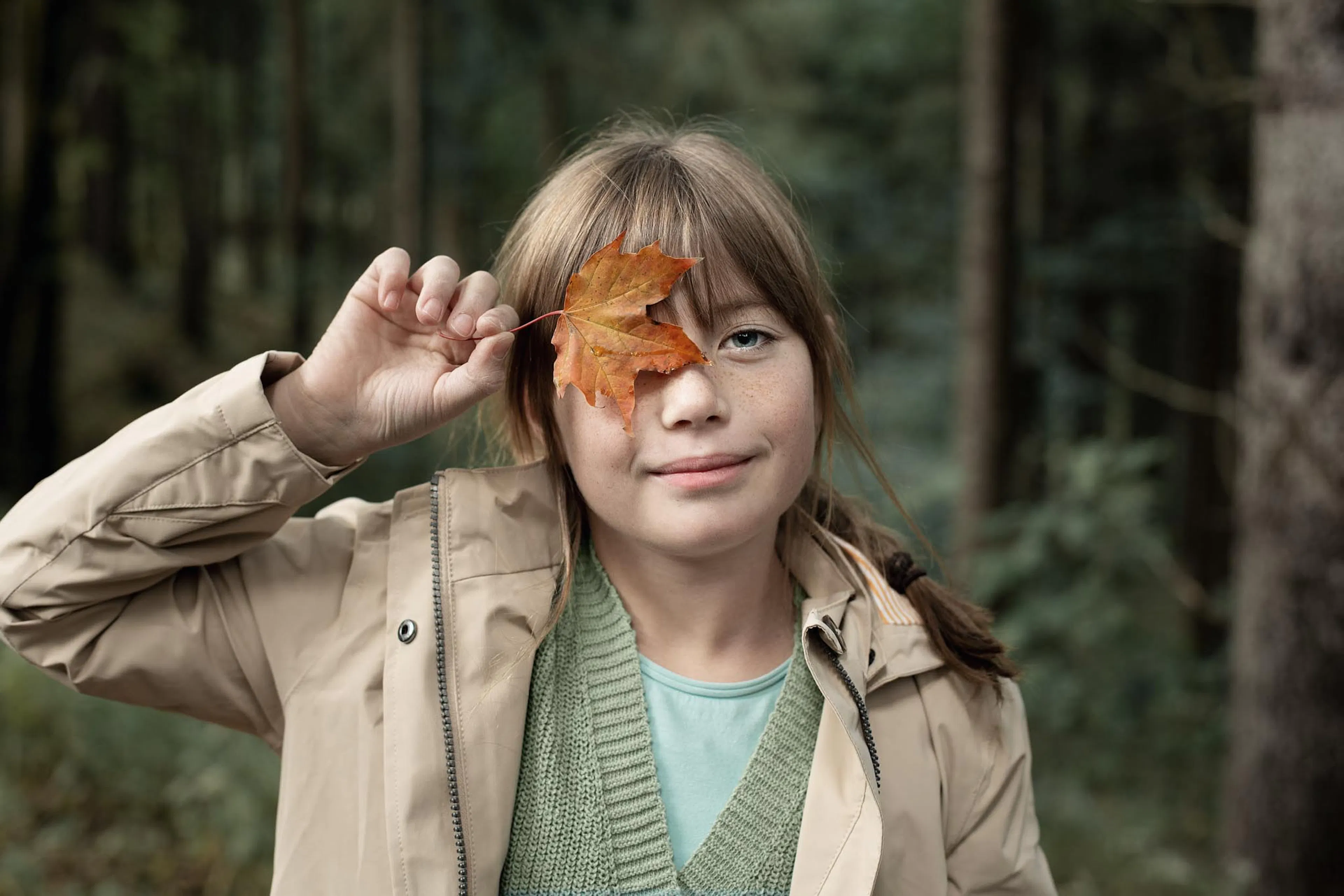 Girl playing with leaves in the forest in autumn.