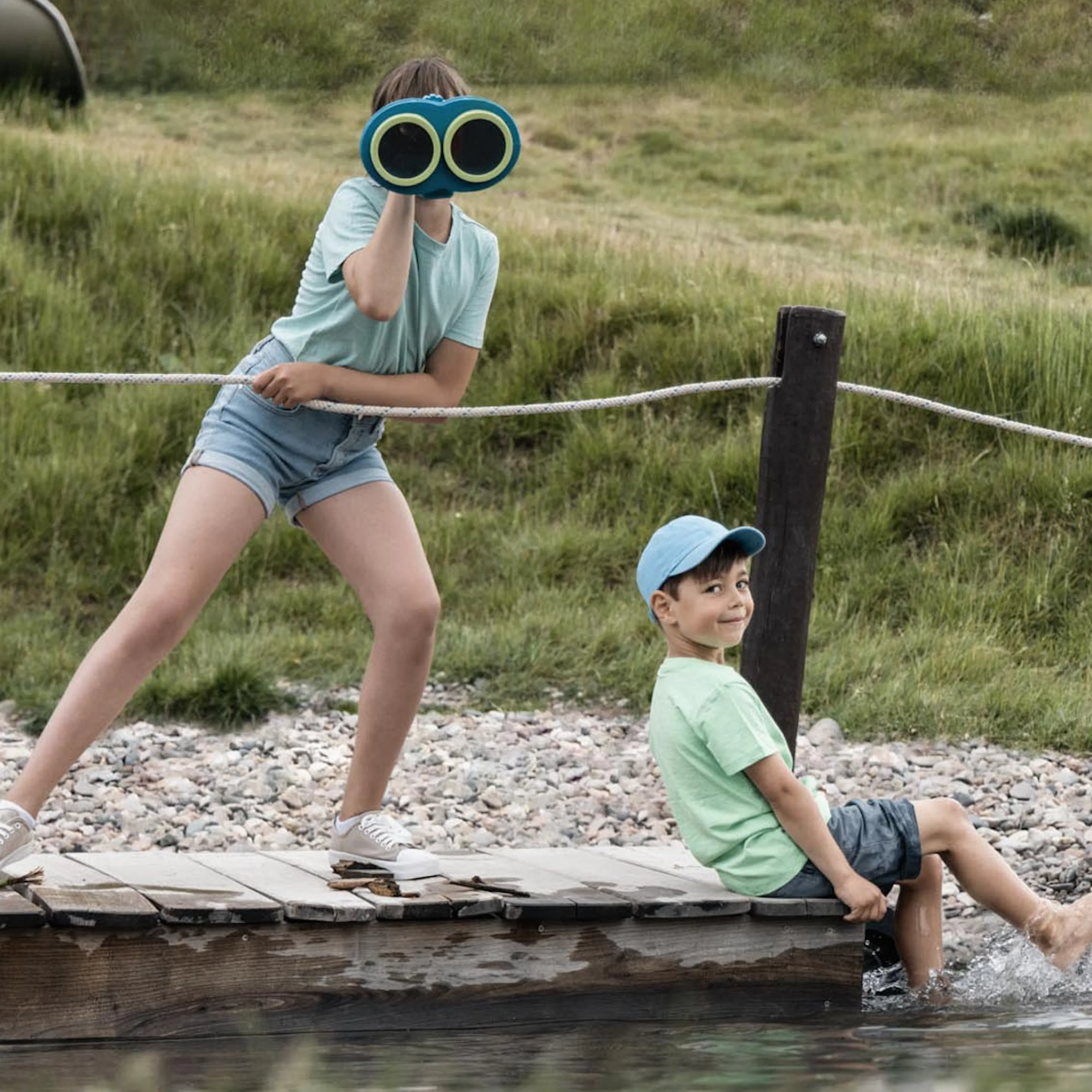 Mädchen und Junge spielen auf dem Floss auf dem Spielplatz des The Grand Green - Familux Resorts.