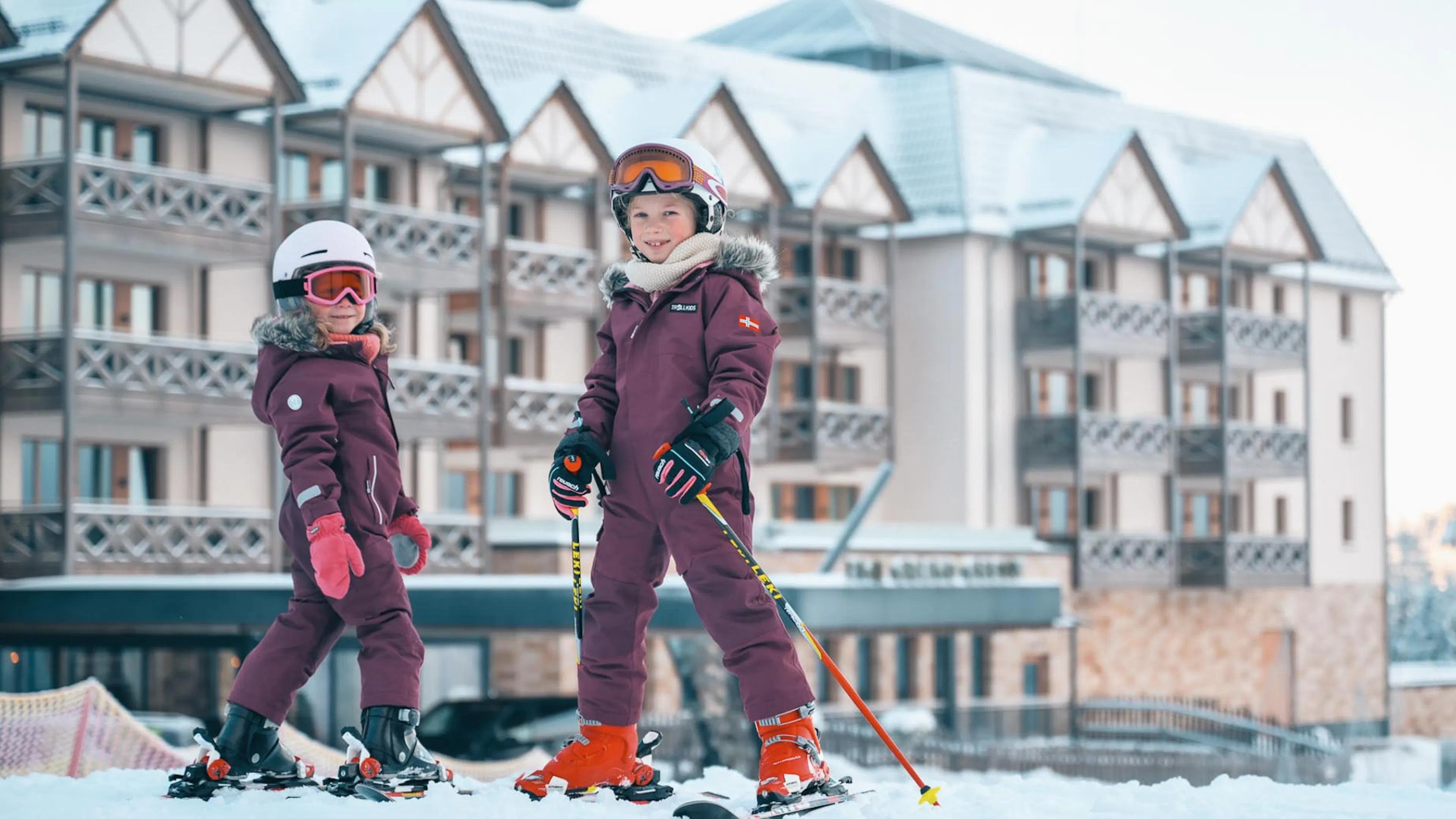 Two girls in ski outfits at a ski lesson in front of The Grand Green – Familux Resort.