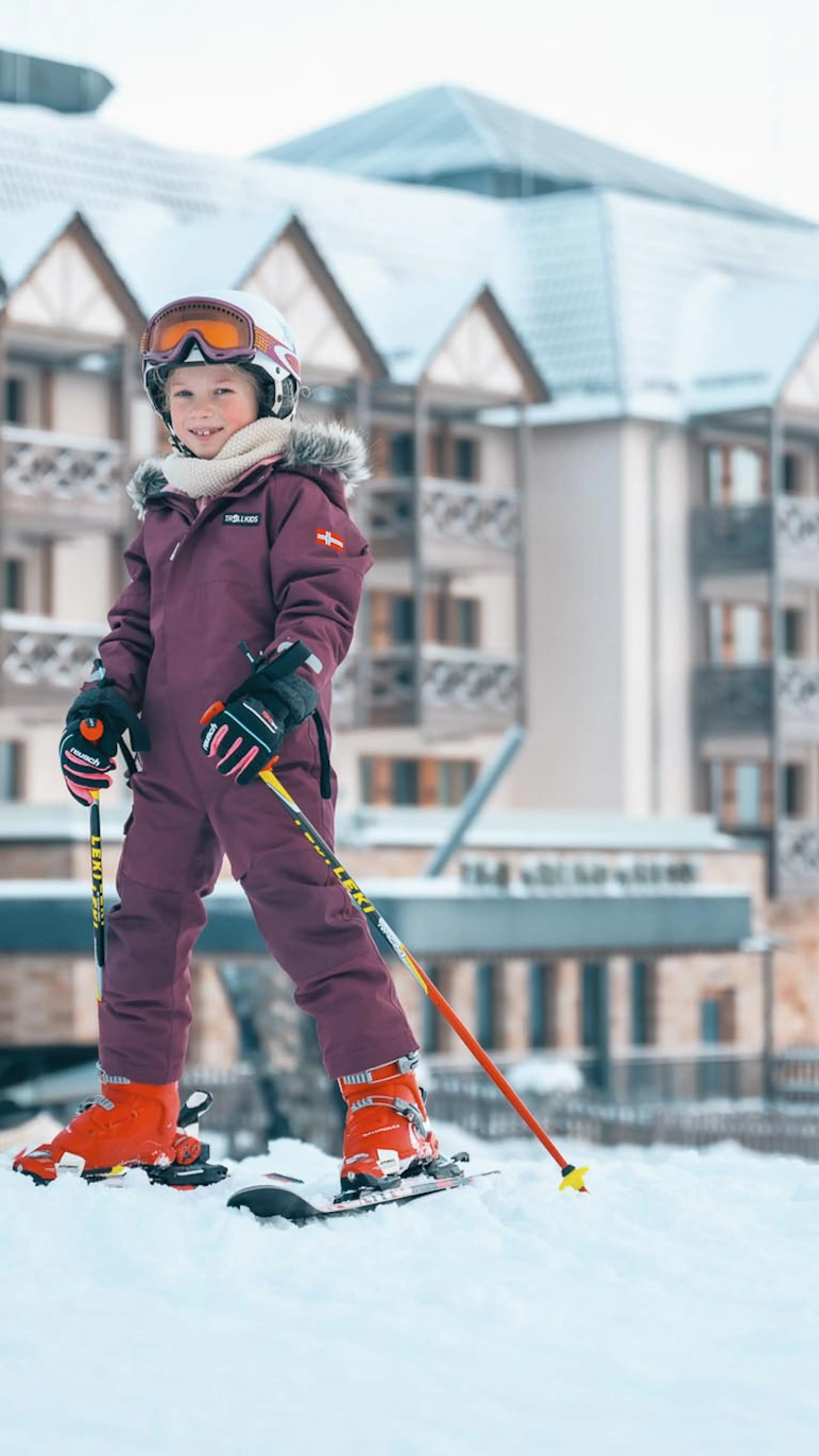 Zwei Mädchen im Skioutfit beim Skikurs vor dem The Grand Green - Familux Resort.