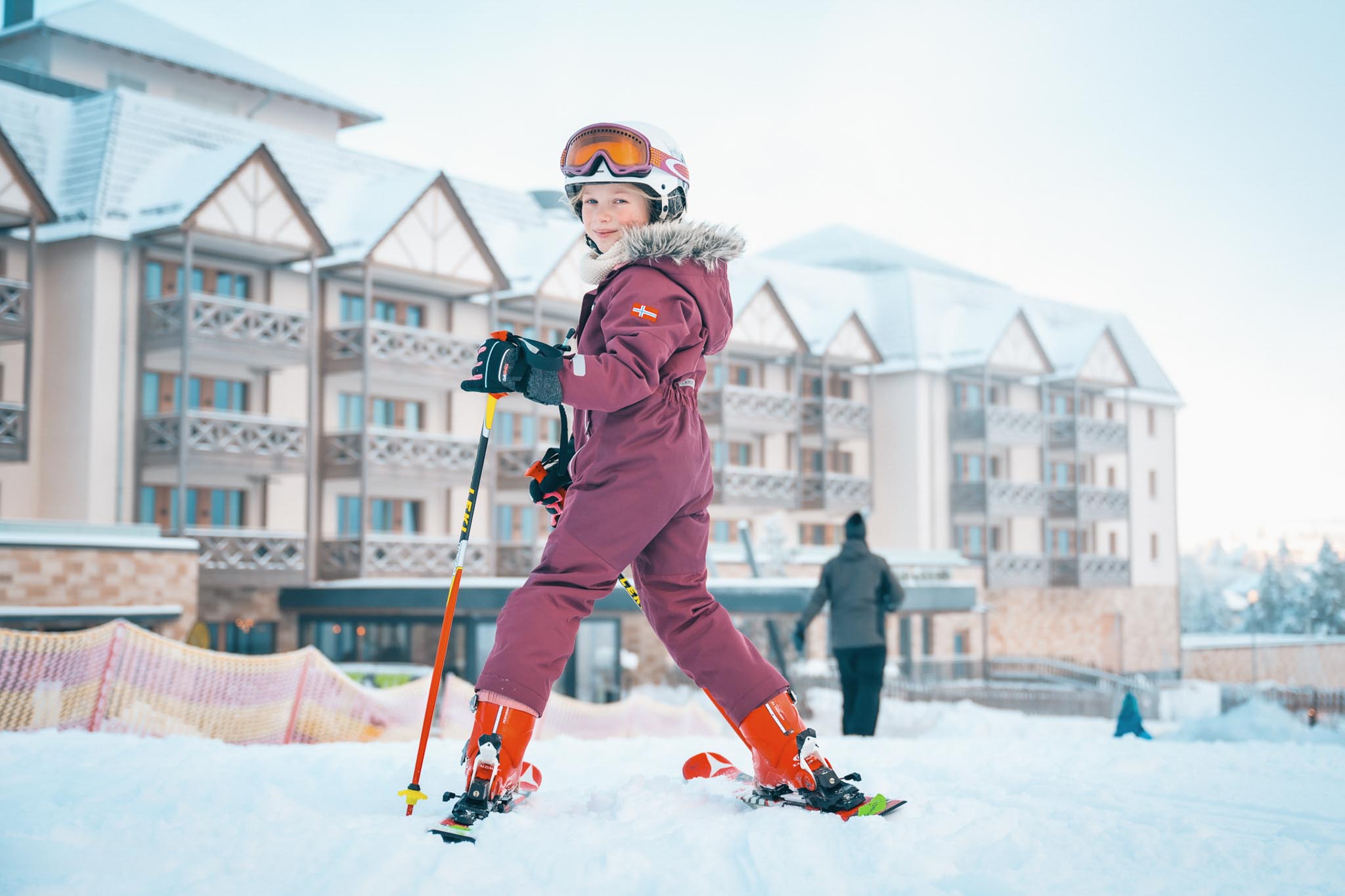 Girl in ski outfit at a ski lesson in front of The Grand Green – Familux Resort.