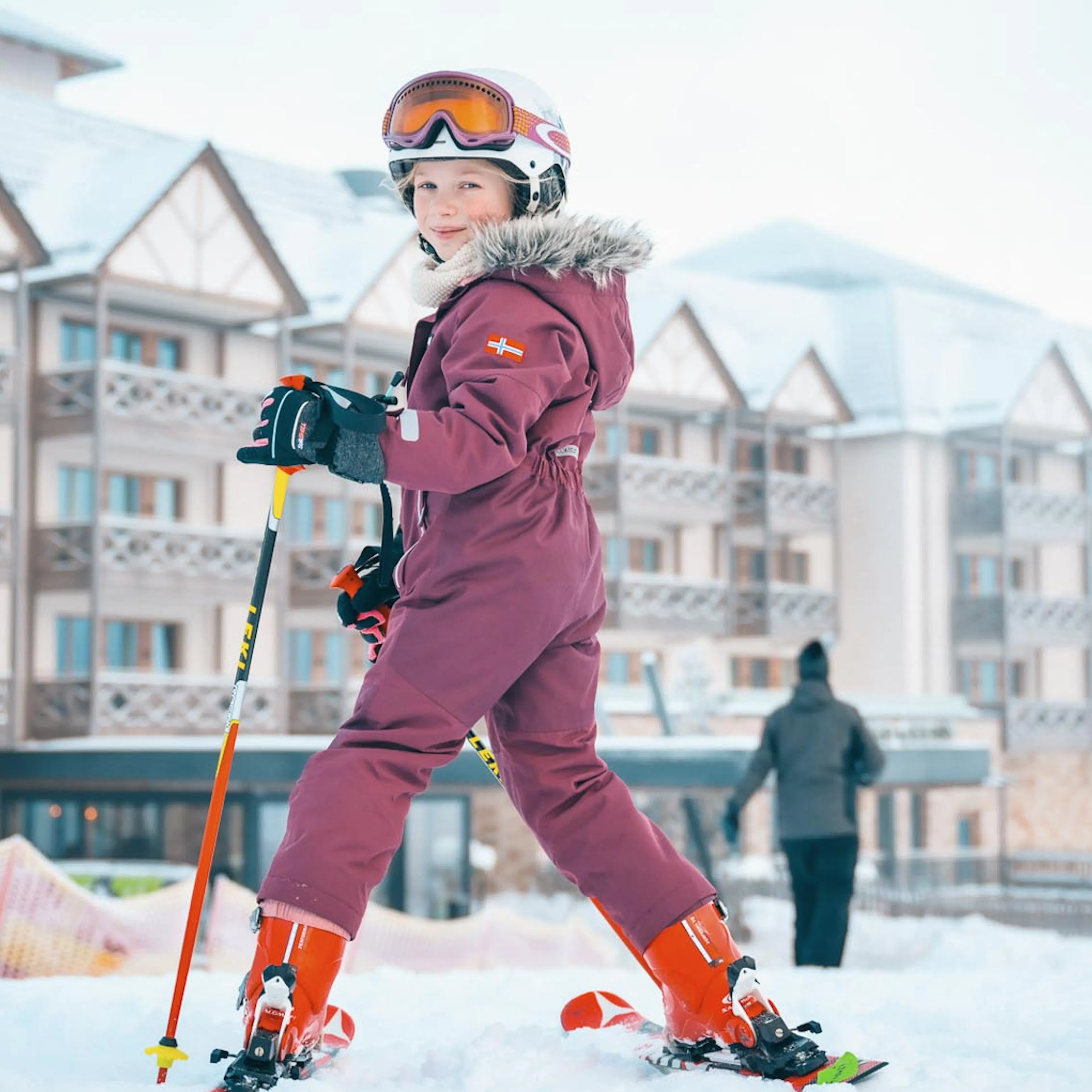 Girl in ski outfit at a ski lesson in front of The Grand Green – Familux Resort.