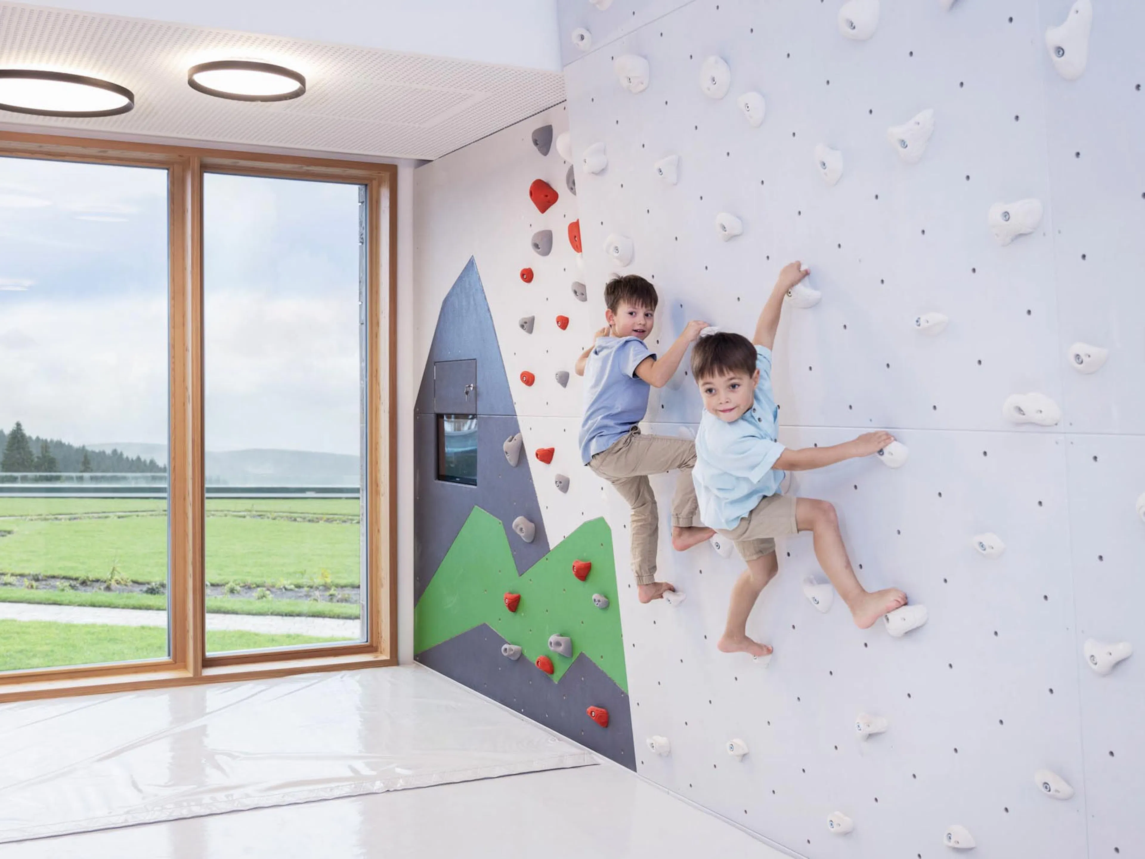 Two boys climbing on the climbing wall in the Kids Club at The Grand Green – Familux Resort.