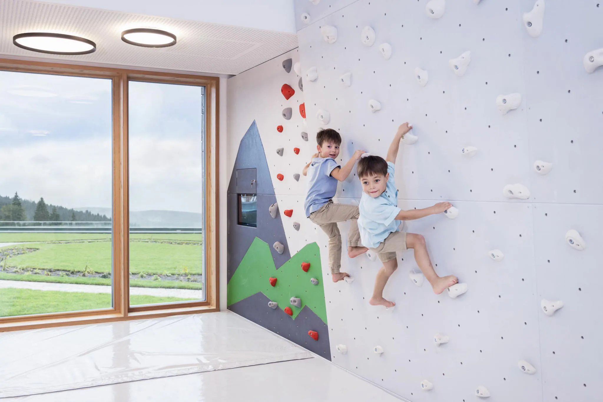 Zwei Jungs klettern an der Kletterwand im Kids Club des The Grand Green - Familux Resorts.