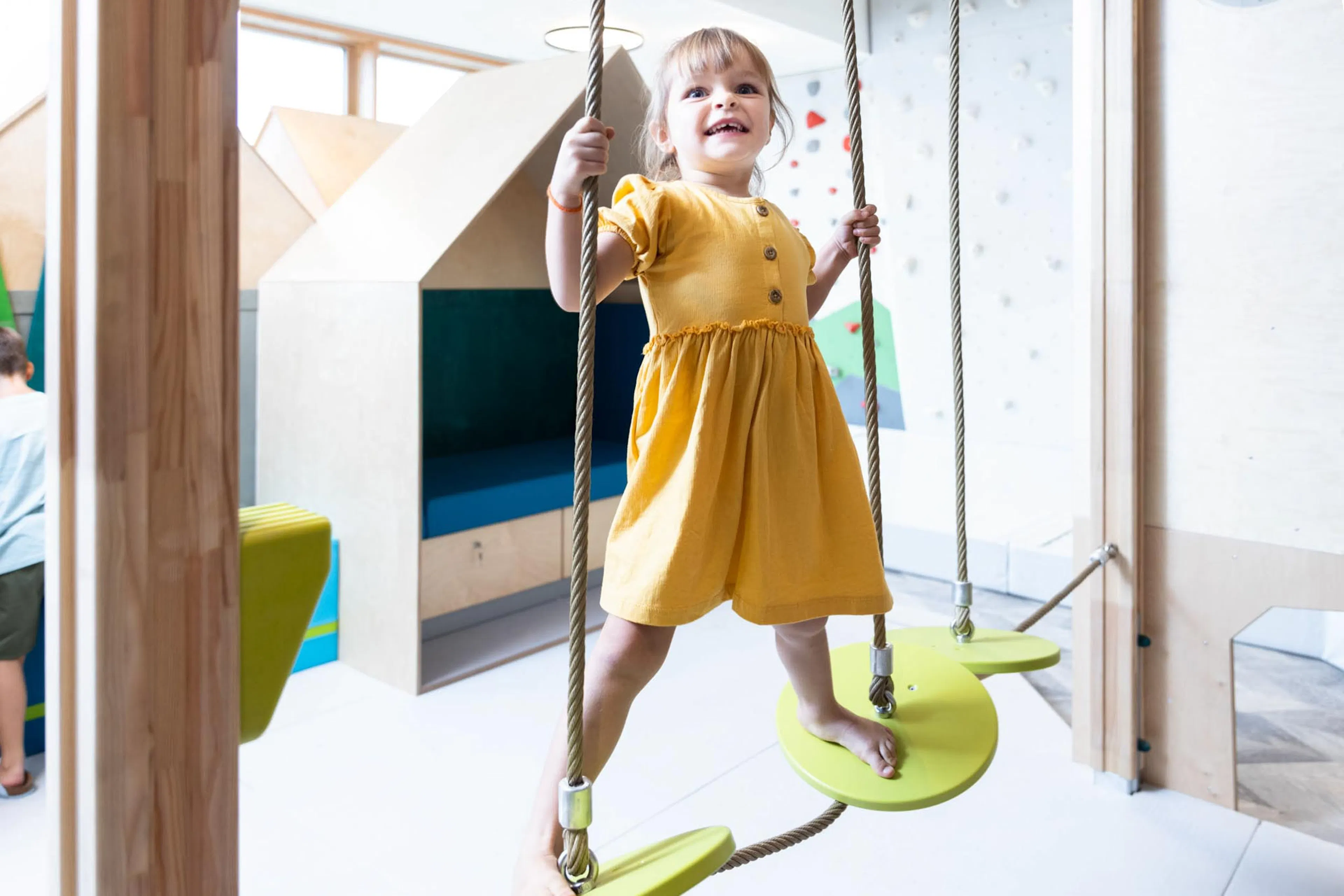 Mädchen klettert am Kletterturm im Kids Club des The Grand Green - Familux Resorts.
