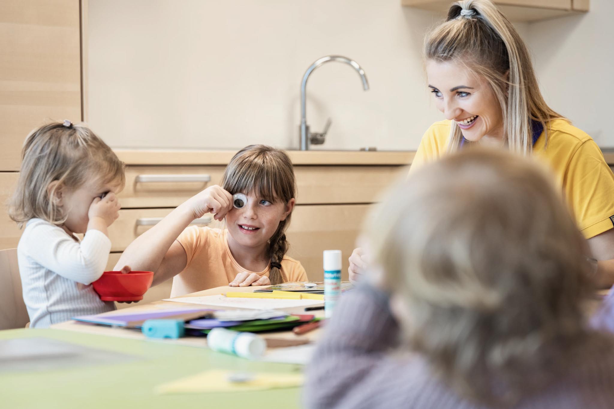 Children doing crafts with a childcare worker in the Kids Club at The Grand Green – Familux Resort.