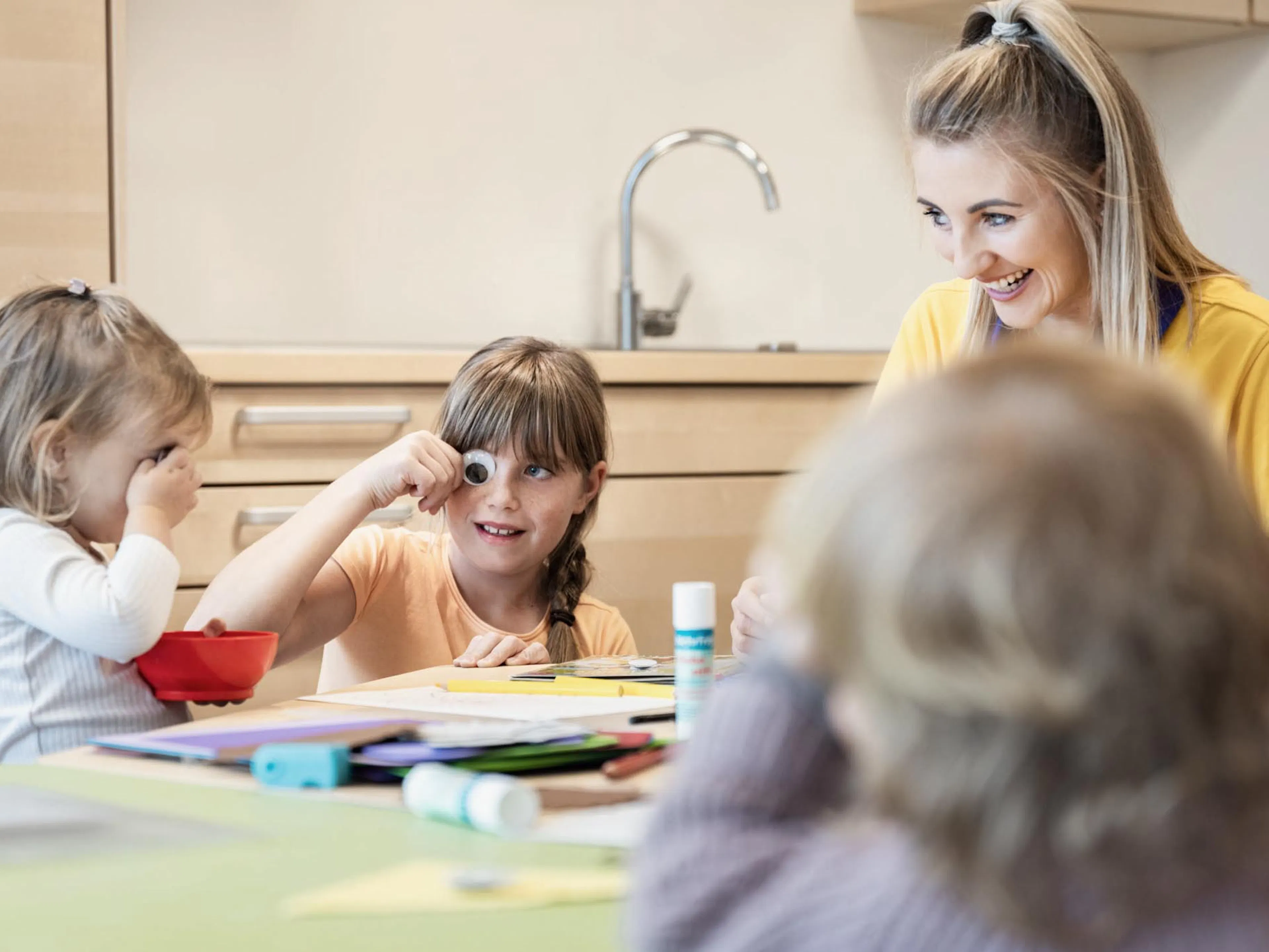 Children doing crafts with a childcare worker in the Kids Club at The Grand Green – Familux Resort.