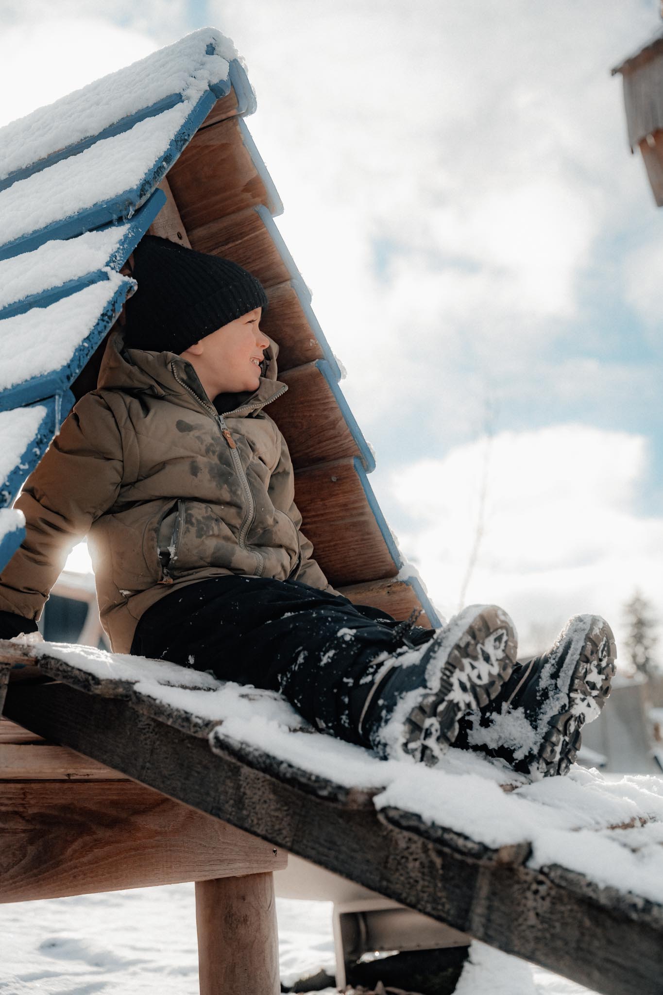 Child playing in a playhouse in the garden of The Grand Green – Familux Resort in winter.