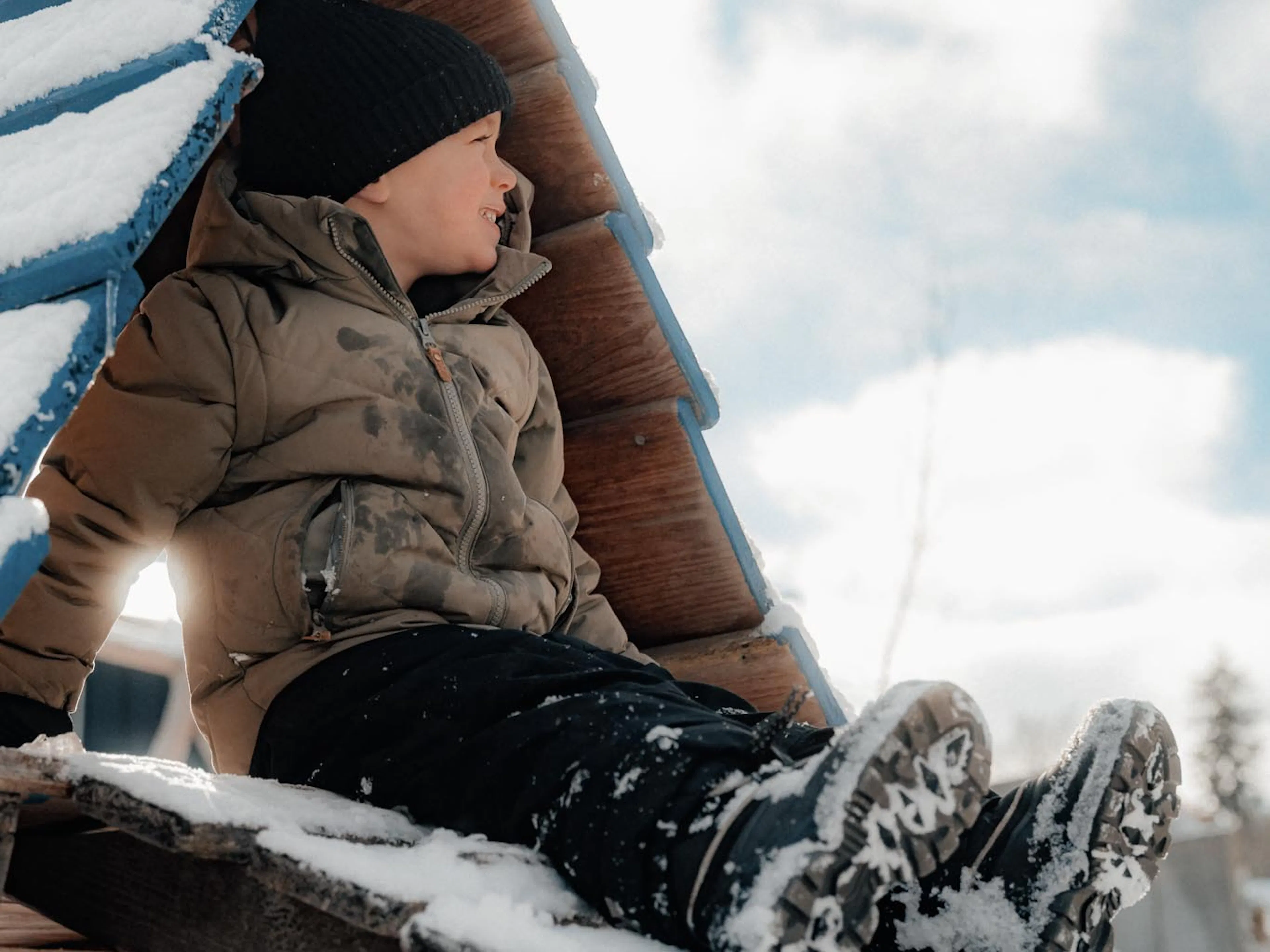 Child playing in a playhouse in the garden of The Grand Green – Familux Resort in winter.