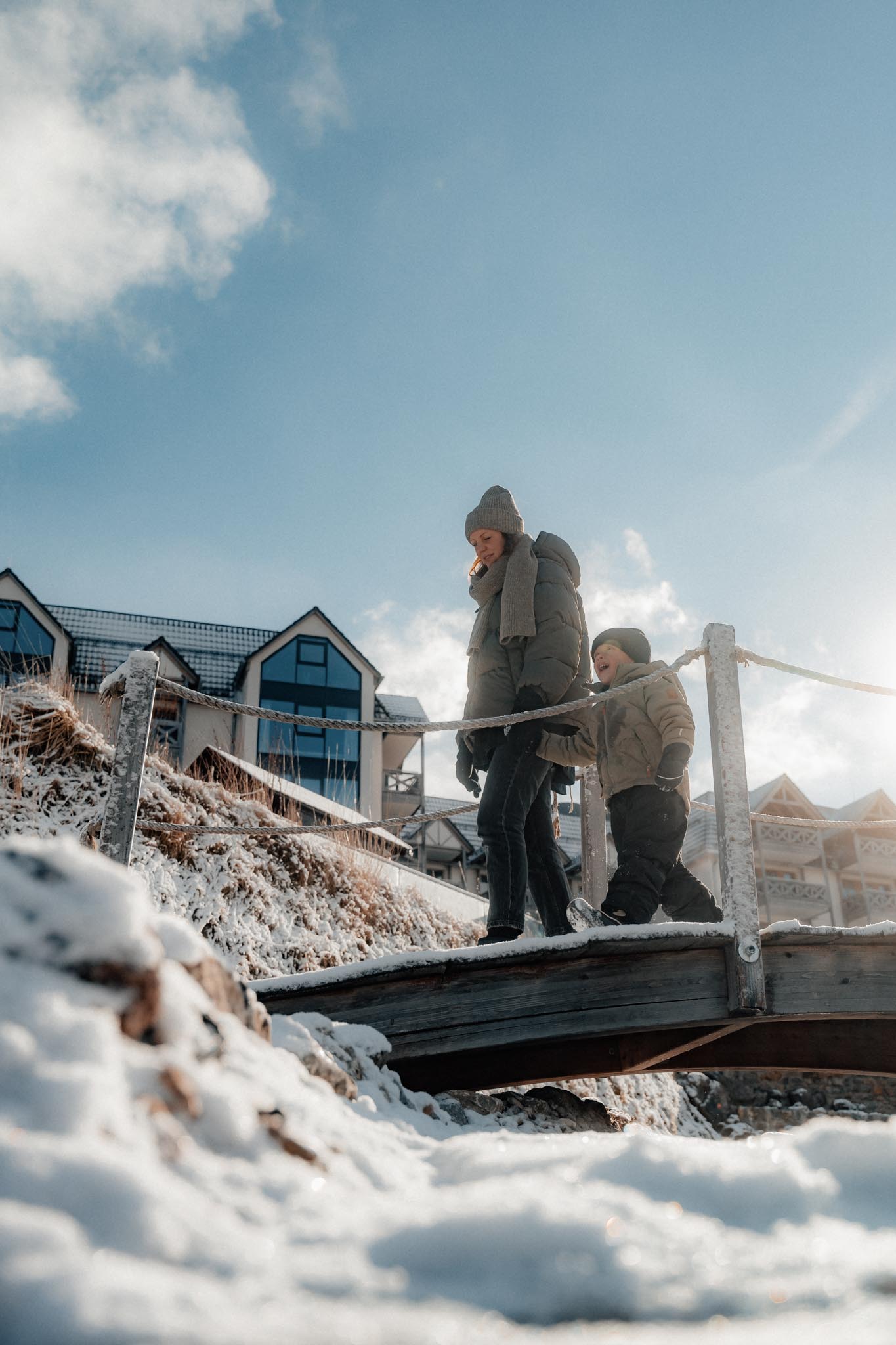 Mother walking with her child in the hotel gardens of The Grand Green – Familux Resort in winter.