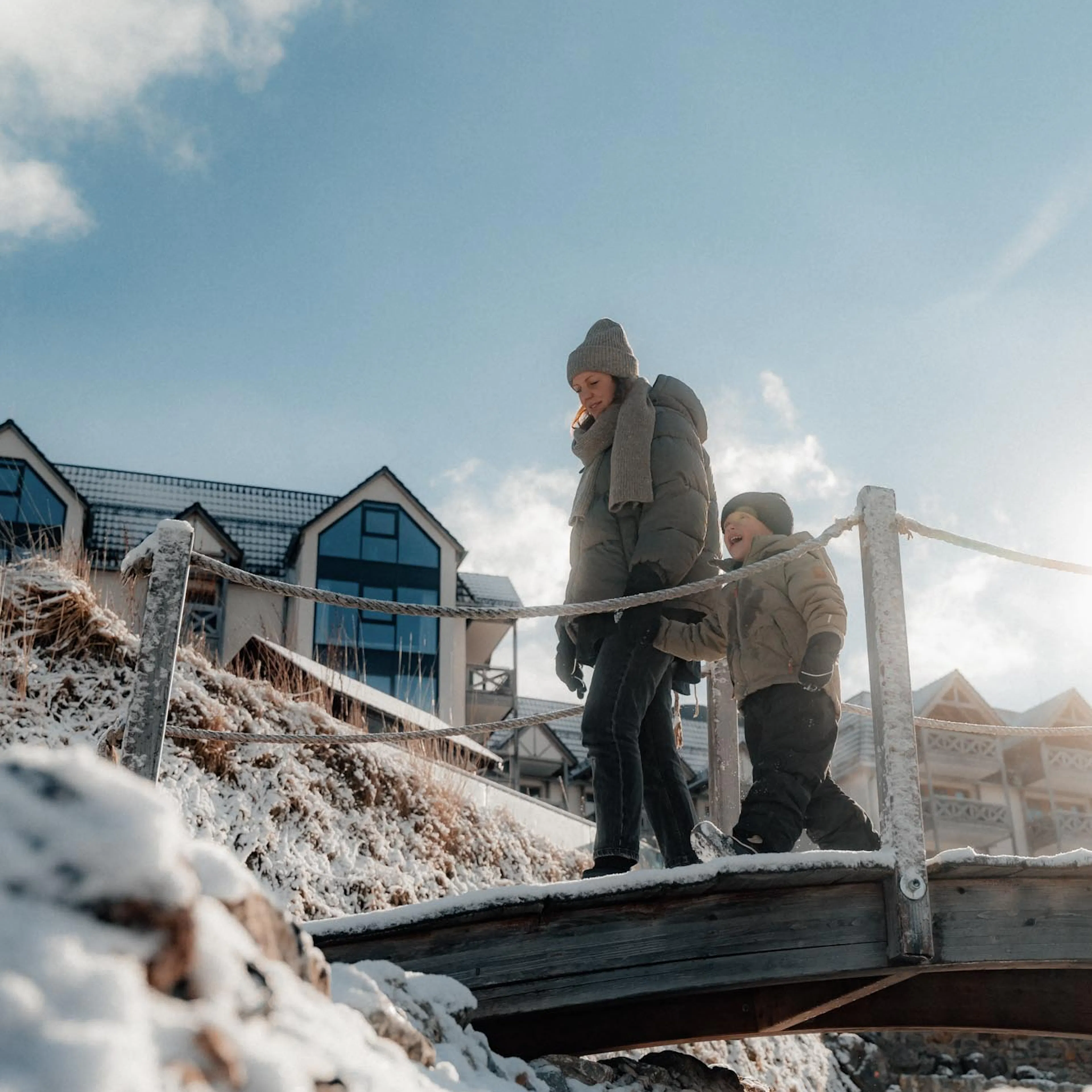 Mother walking with her child in the hotel gardens of The Grand Green – Familux Resort in winter.